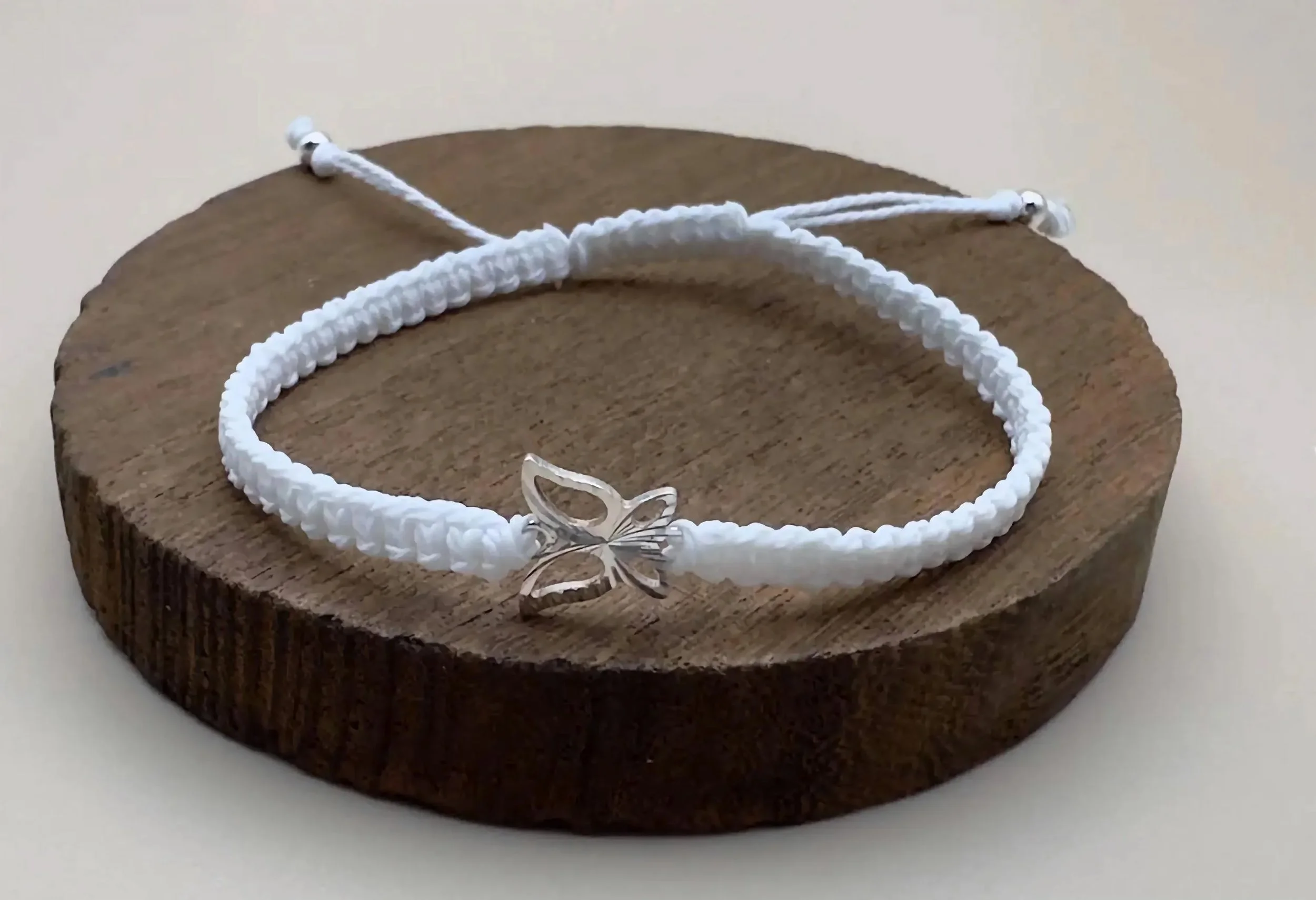 close-up of the silver-wing bracelet highlighting the polished finish of the .925 silver and the intricate white knots.
