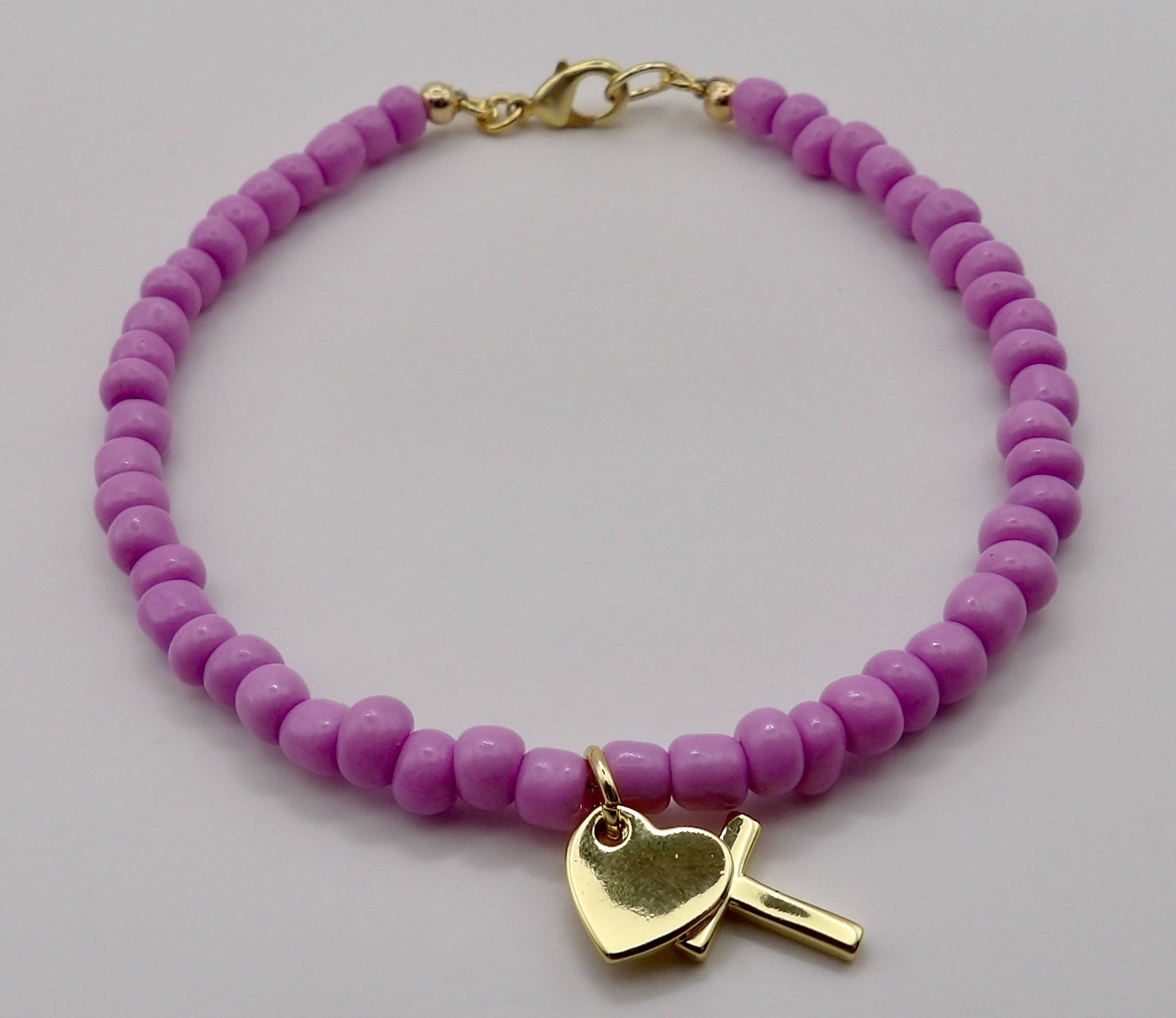 handmade dainty seed bead bracelet in lilac (custom colors available) featuring hanging 18k gold cross and heart charms.