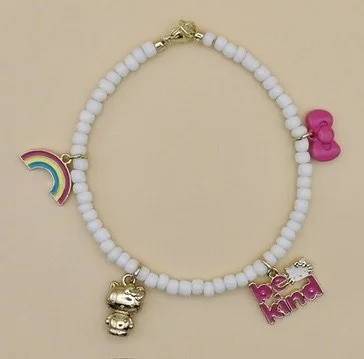 close-up detail of the 18k solid gold hollow puffy hello kitty charm on the handmade white bead bracelet.