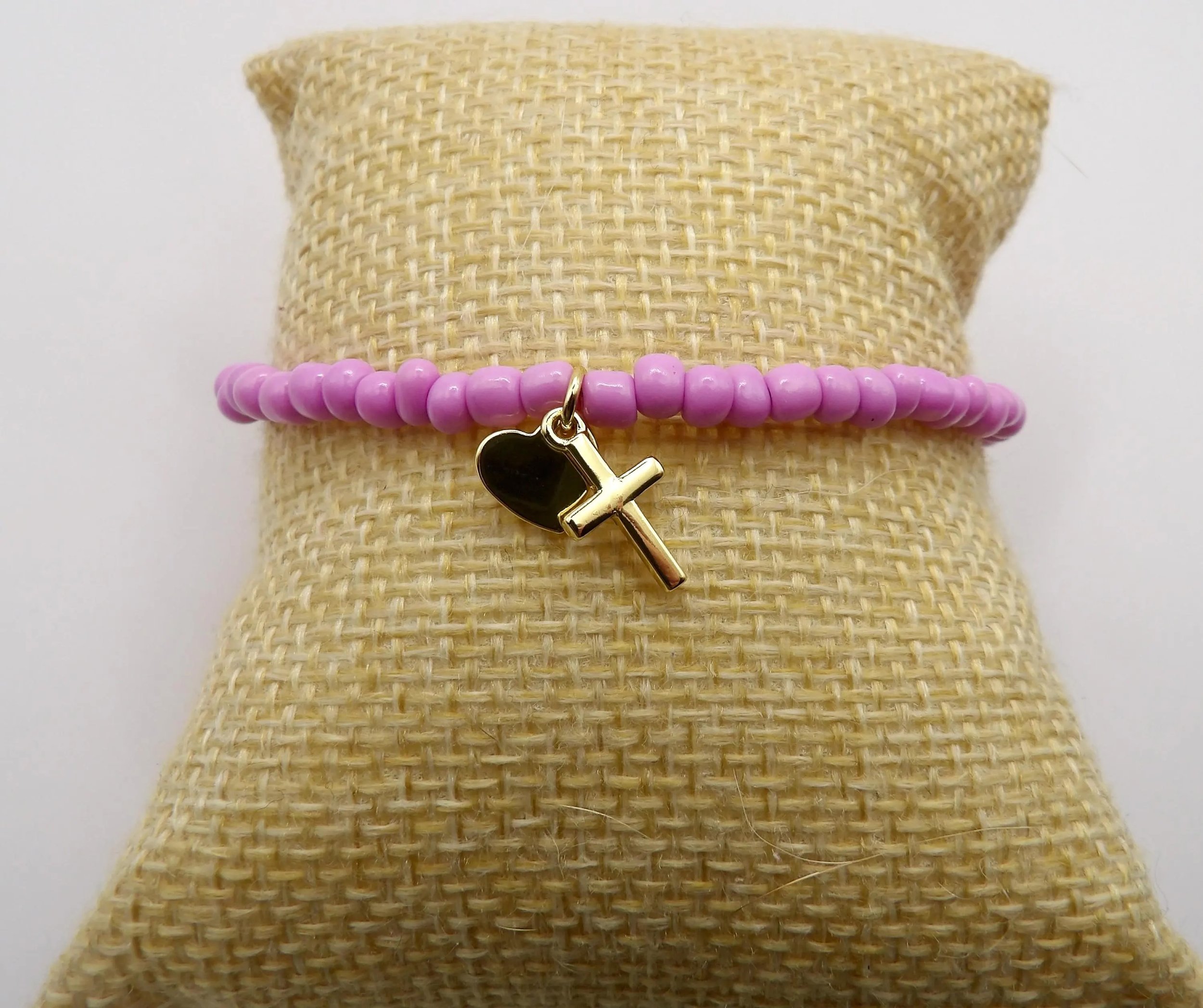 close-up of the faithful minimalist bracelet highlighting the high-shine gold cross and heart charms.