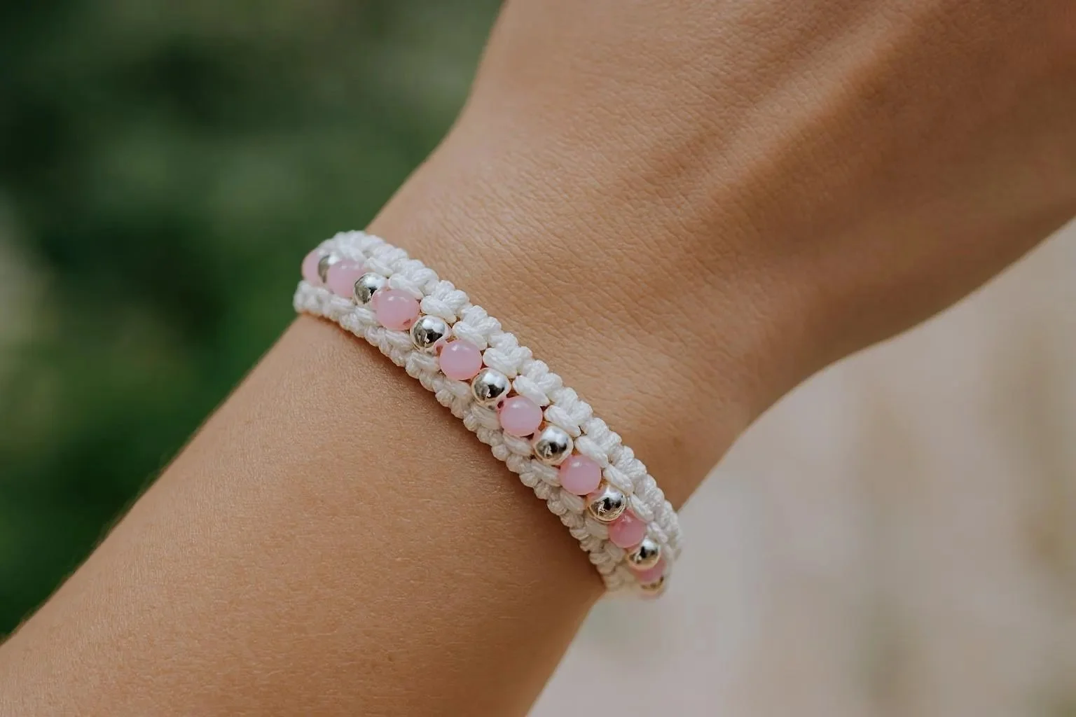 the detailed dreamer bracelet featuring intricate white macramé weaving accented by sterling silver beads and soft pink seed beads.