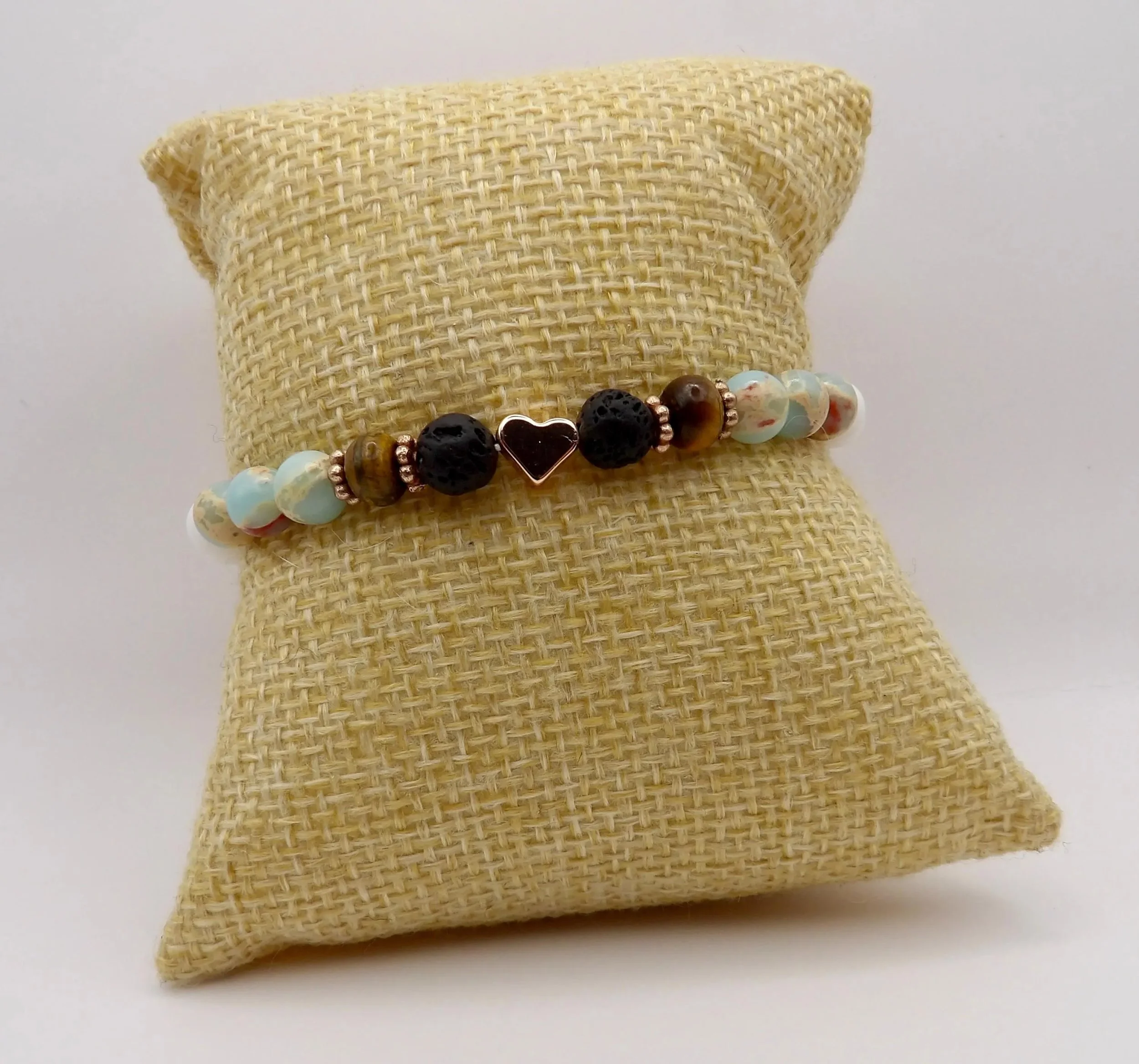 detailed view of the rose gold heart centerpiece and the absorbent lava beads in this artisan-made aromatherapy piece.