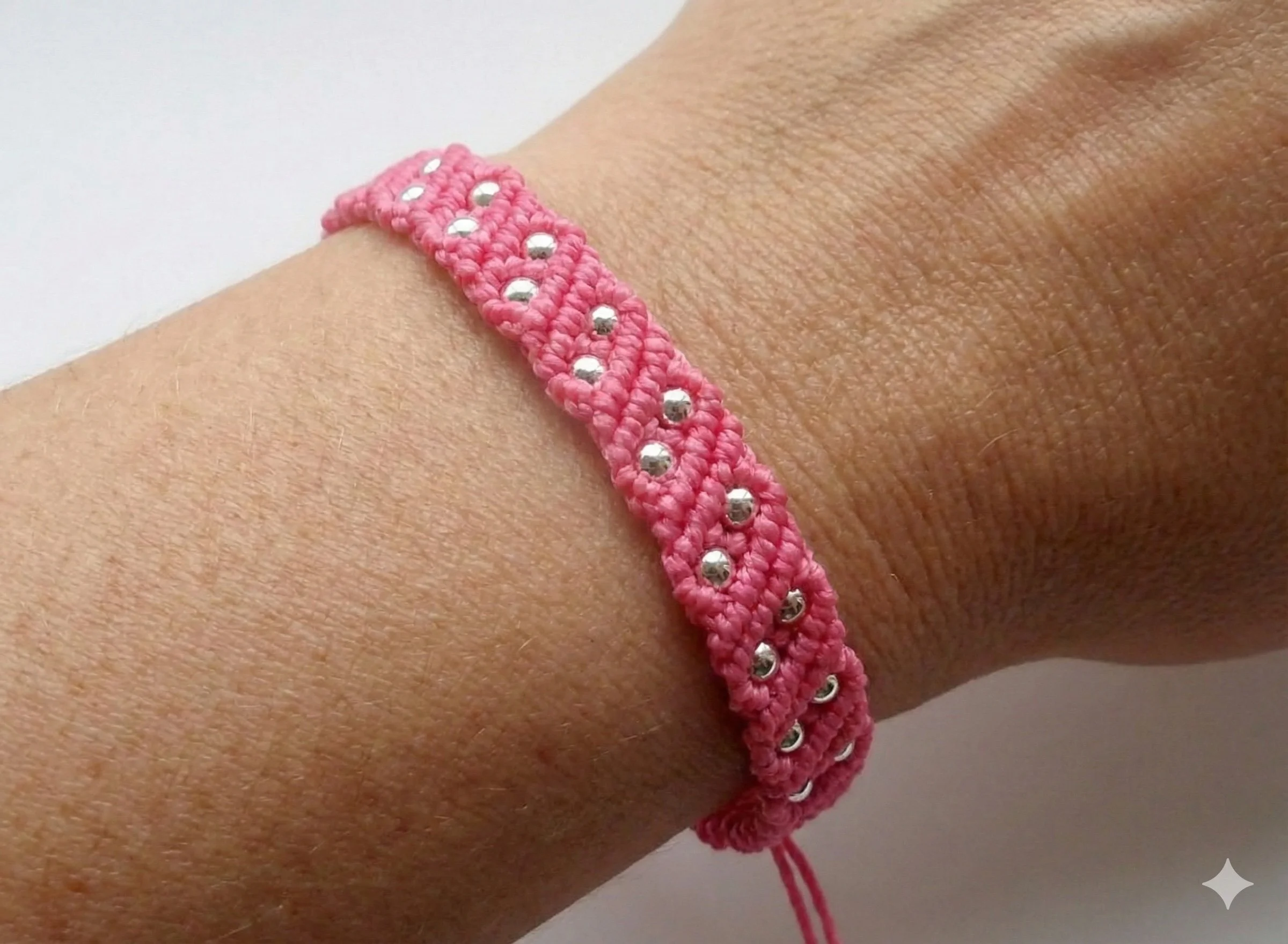 hot pink micro-macramé bracelet on a wrist featuring tiny 3mm sterling silver bead accents.