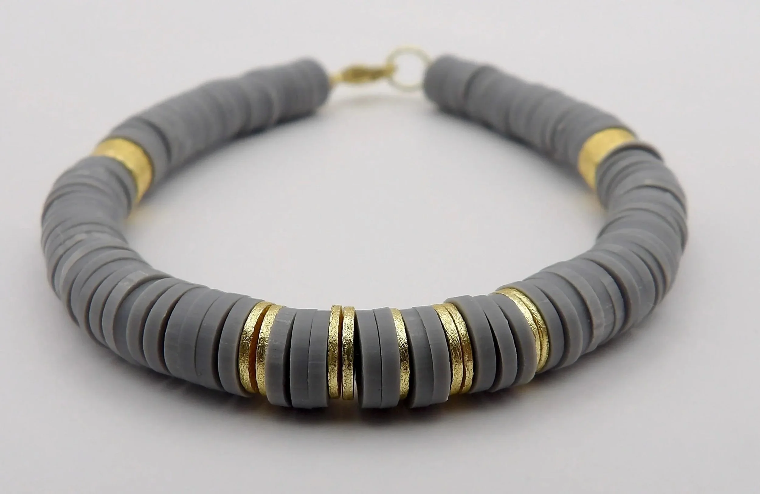 minimalist gray and gold stretch bracelet showing the contrast between soft matte heishi beads and a brushed metallic focal.