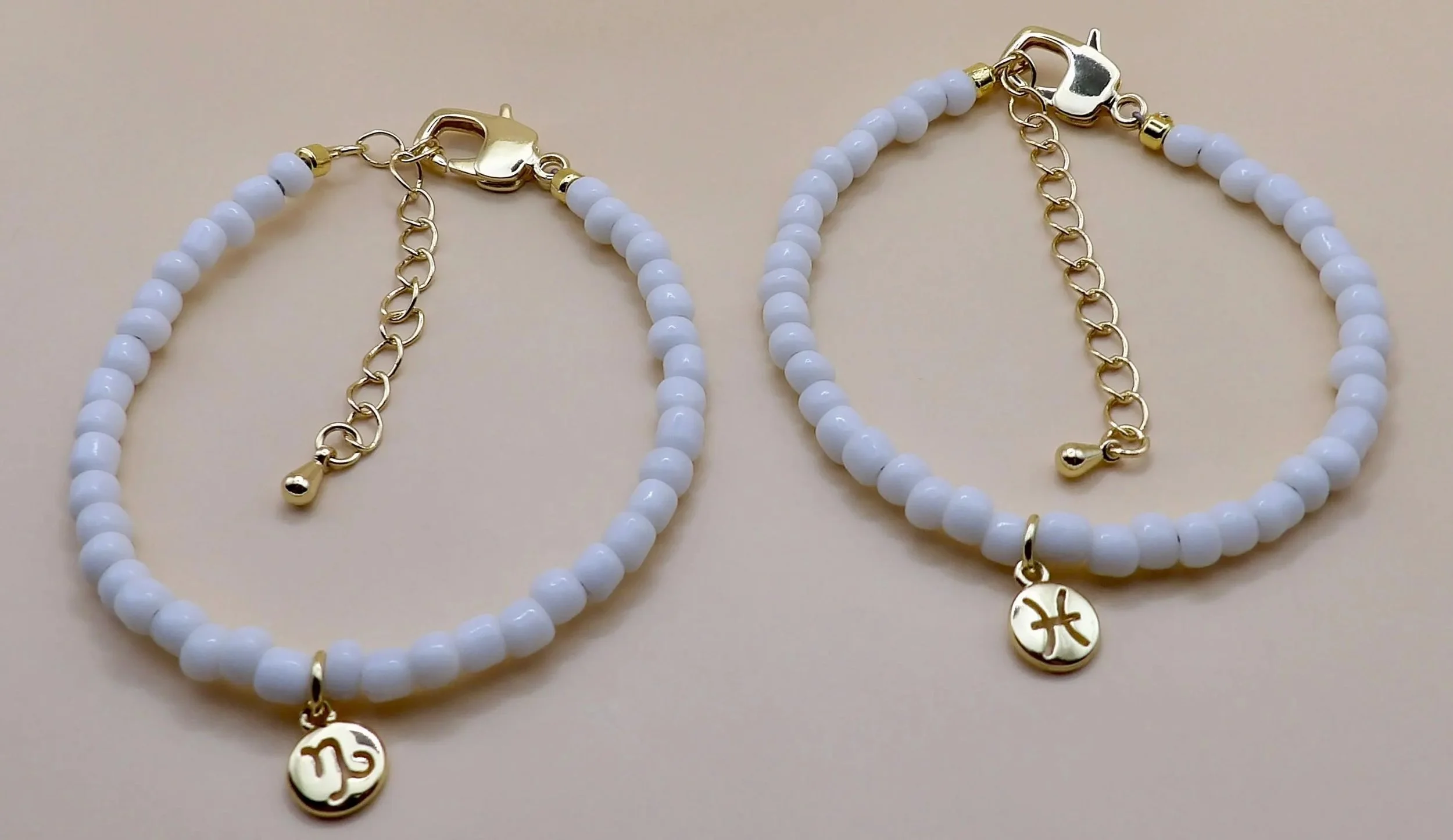 handcrafted astrology-inspired bracelet with white beads and a polished gold-plated zodiac symbol.