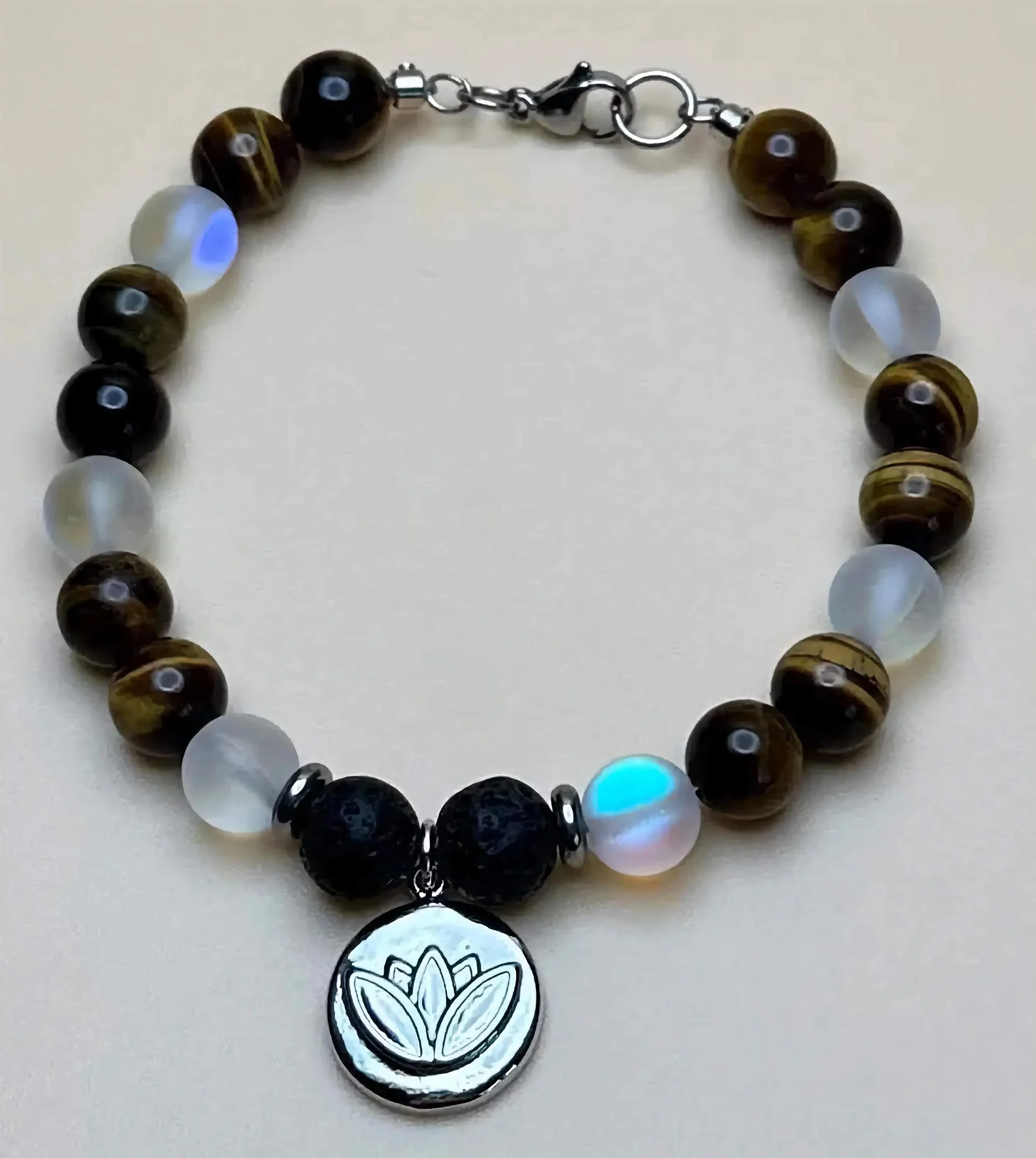 the creative spirit bracelet styled on a neutral background, showcasing the rich browns of tiger's eye and the labradorescence of spectrolite.