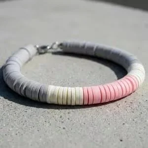 a professional-grade heishi jewelry piece showing the contrast between vibrant pink and muted neutral tones.