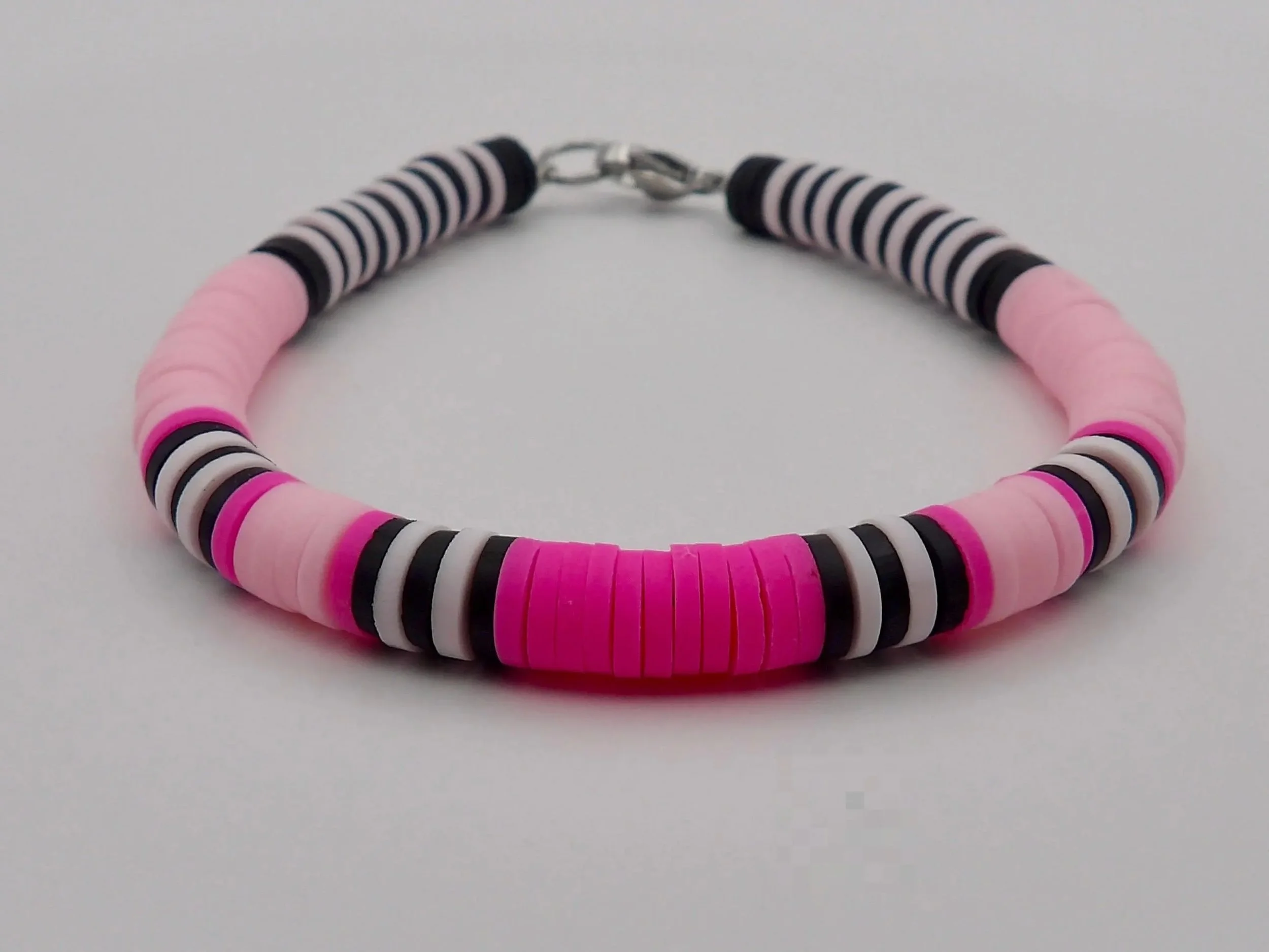 handcrafted symmetrical color-block jewelry with a clean, organized aesthetic in bold pink and black tones.