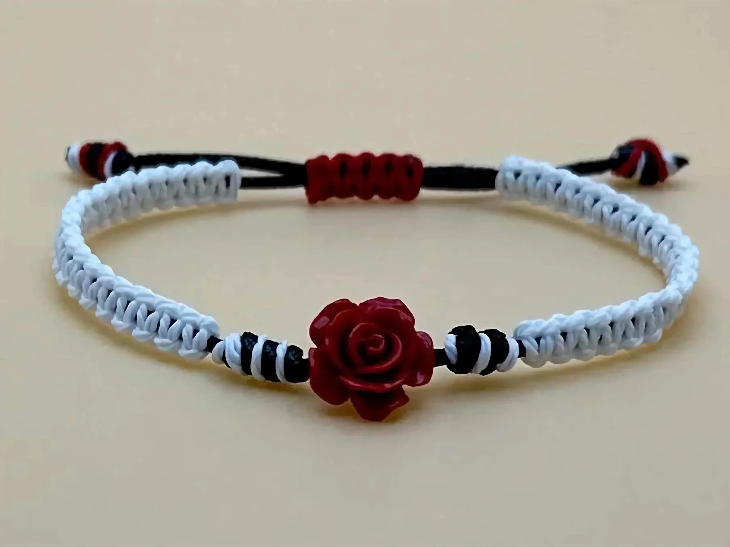 a handcrafted monochrome jewelry piece showing the bold red gemstone rose against a crisp, adjustable woven background.