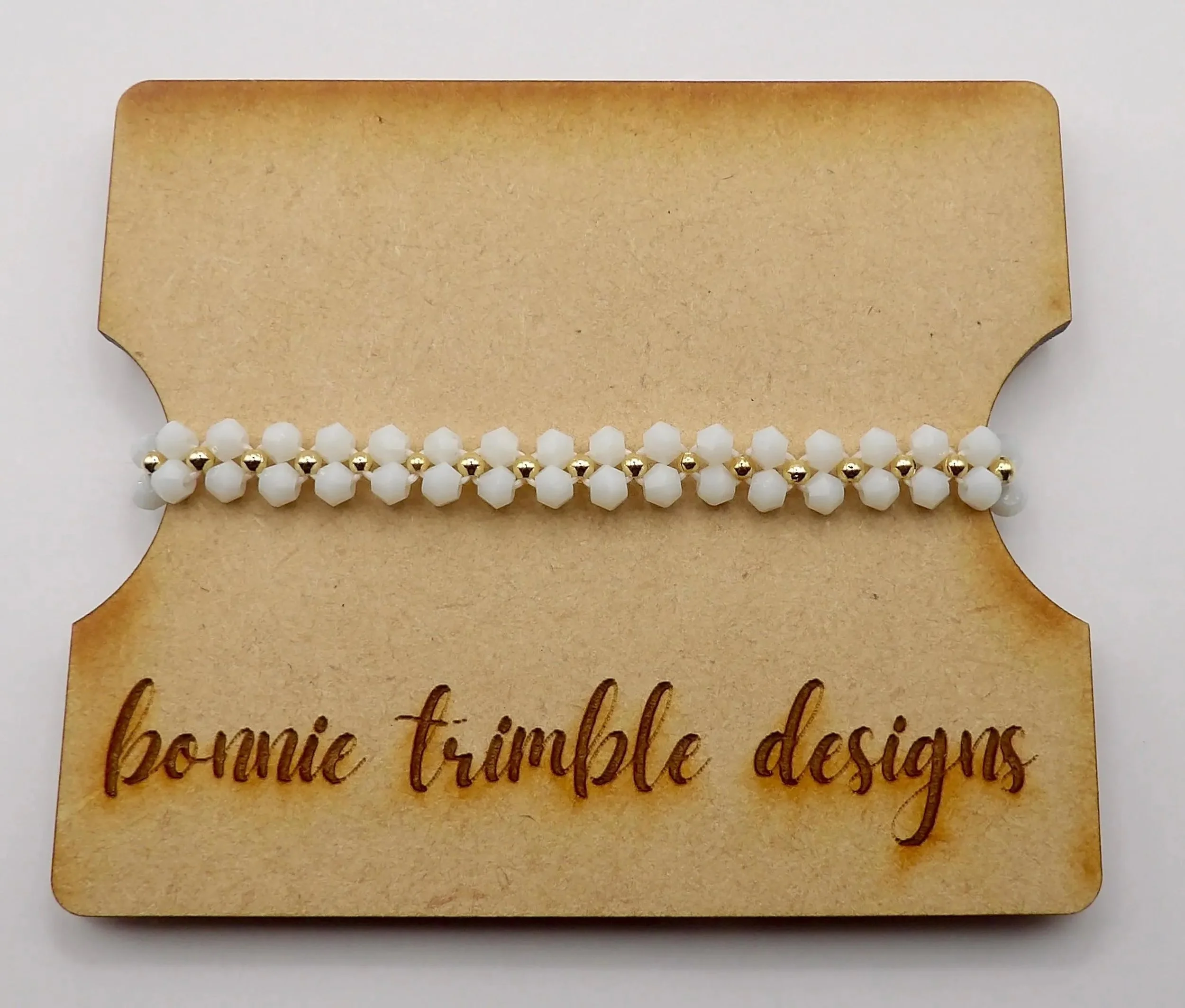 Handcrafted floral bracelet featuring a repeating pattern of white crystal flowers with 18k gold plated focal beads.