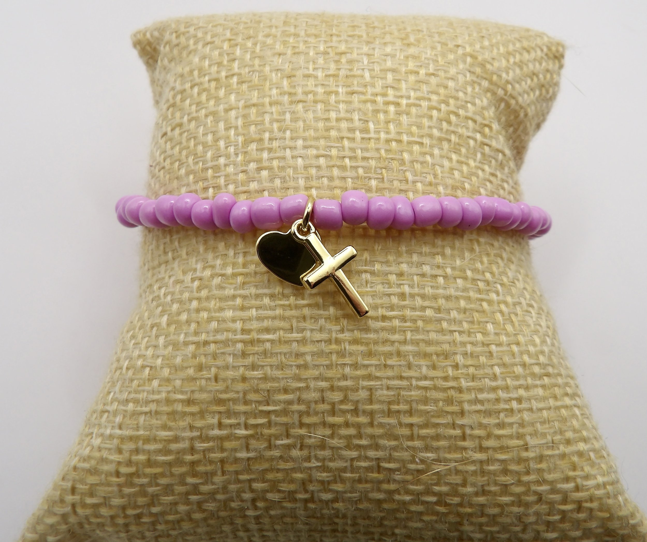 woman wearing the dainty lilac and gold charm bracelet, a meaningful symbol of faith and love.
