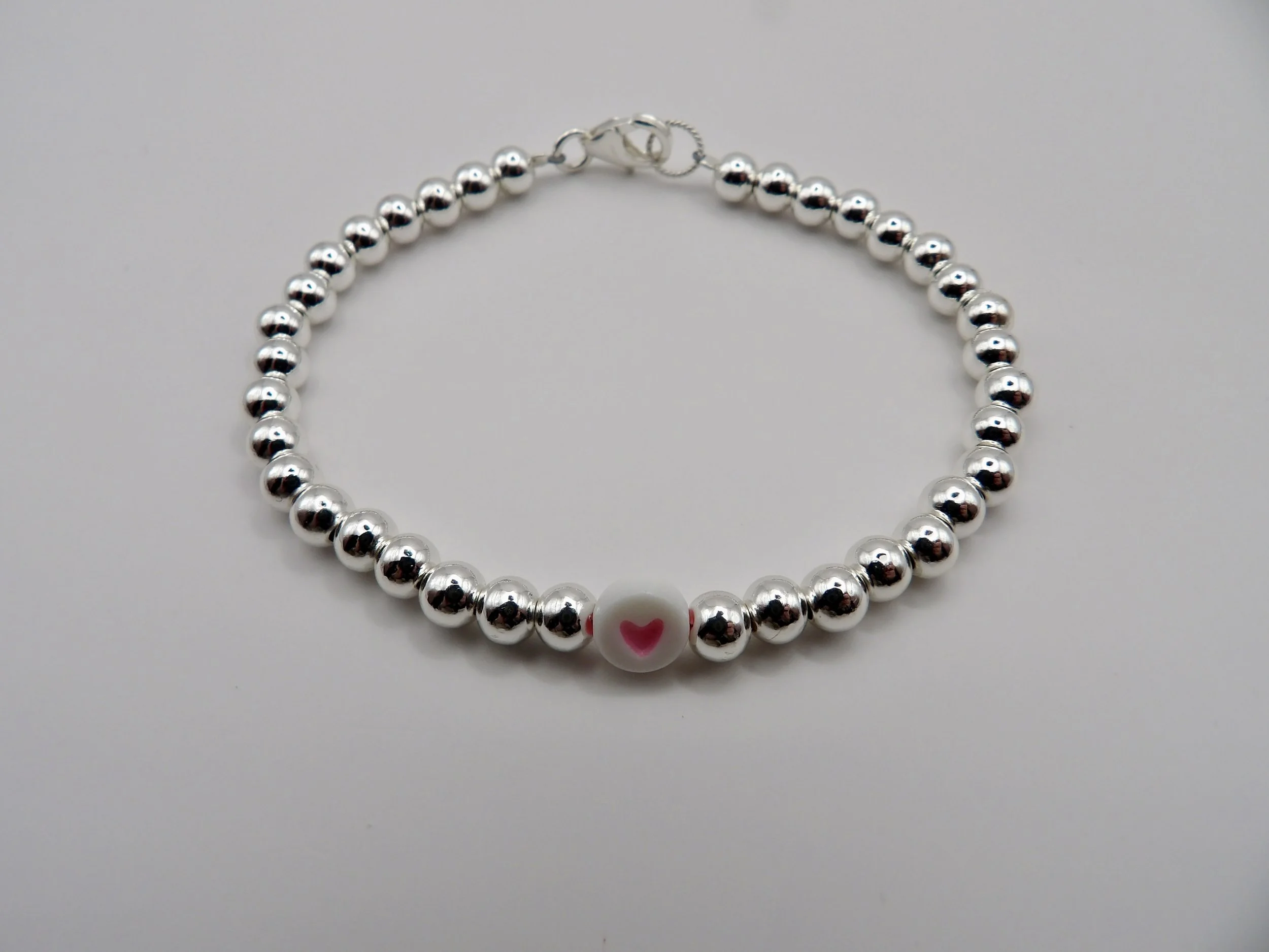 view of the secure sterling silver lobster clasp and twisted jump ring on the 5mm beaded heart bracelet.