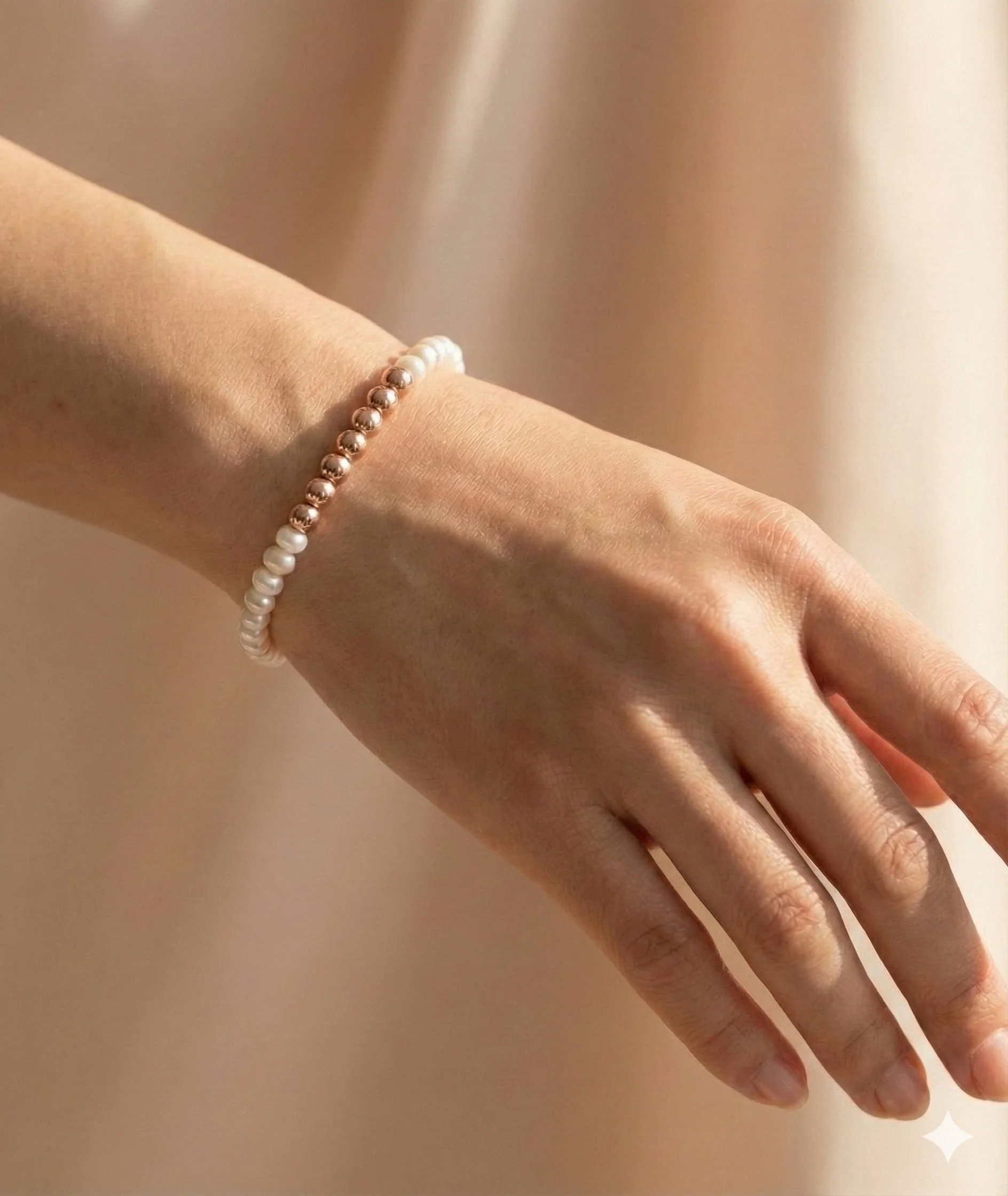 dainty 14k rose gold filled bracelet on a wrist featuring a genuine white freshwater pearl and tiny rose gold beads.