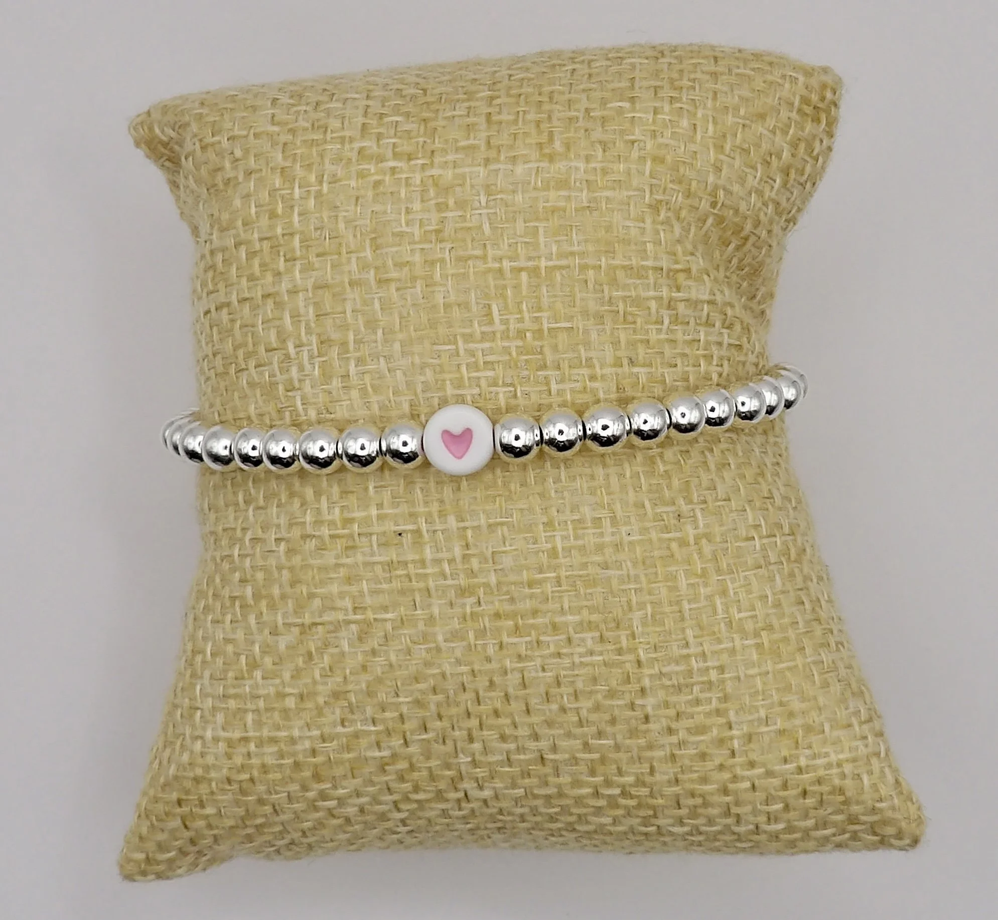 woman wearing the dainty sterling silver pink heart bracelet, showing its minimalist style and suitability for stacking.