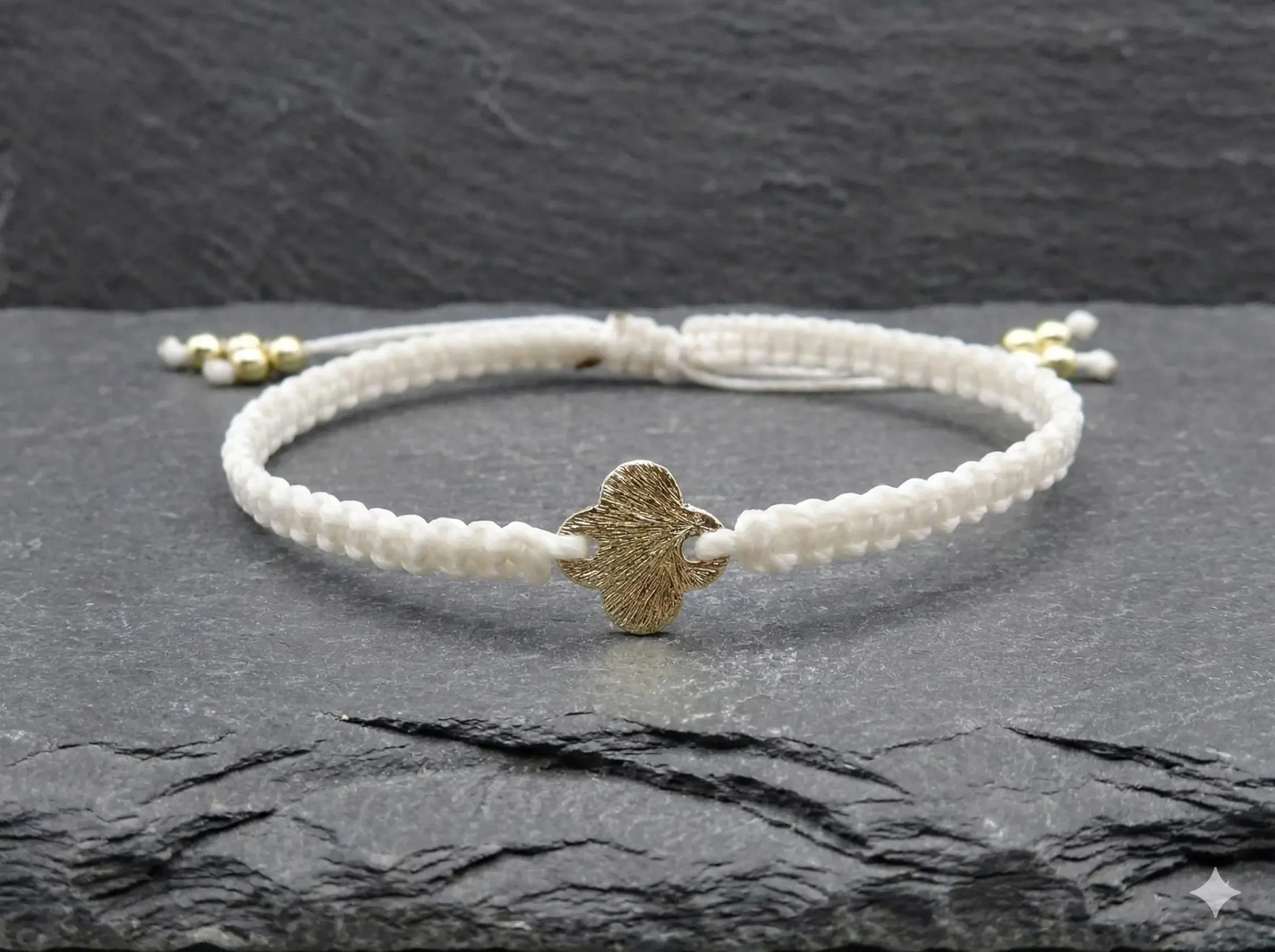 a minimalist faith-inspired cord bracelet showing the detailed texture of the hand-knotted beige macramé and a clean gold cross centerpiece.