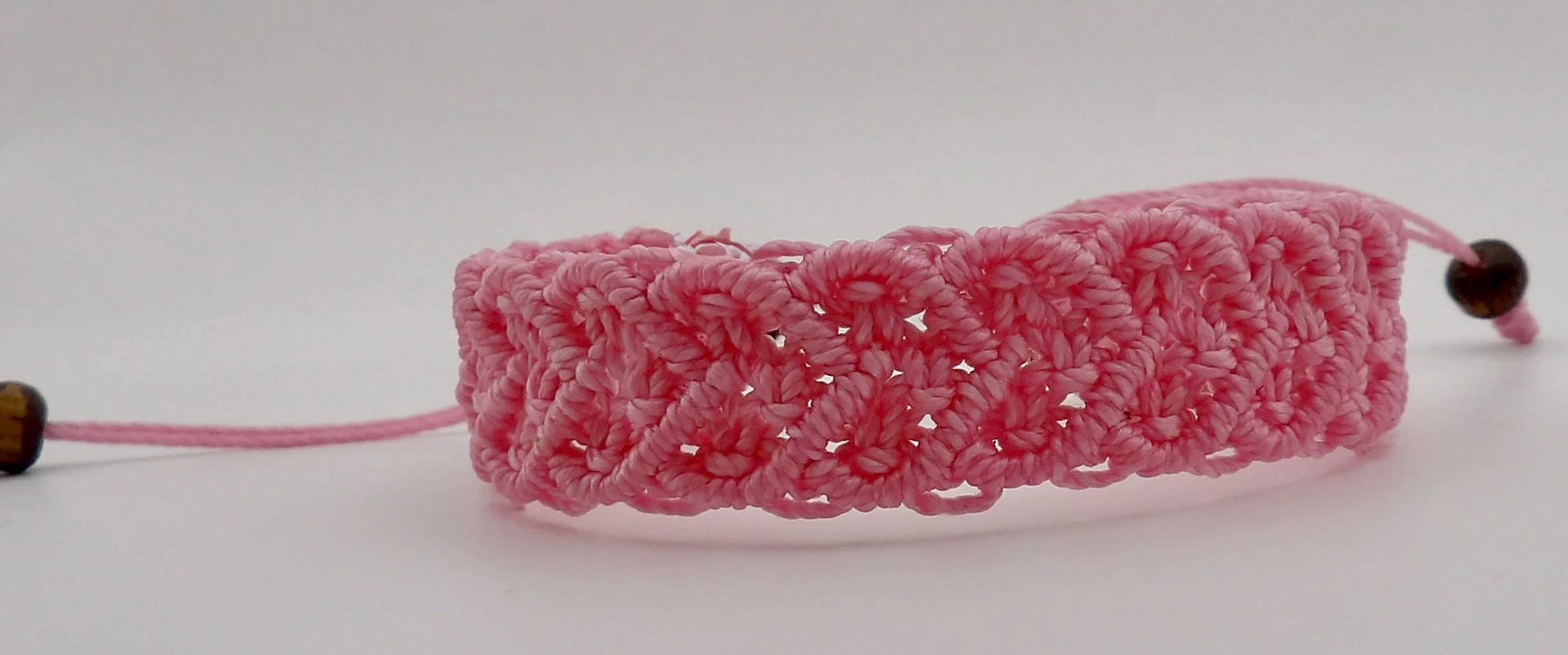 person wearing the wide, statement-style pink macrame heart bracelet, showing the intricate woven texture on the wrist.