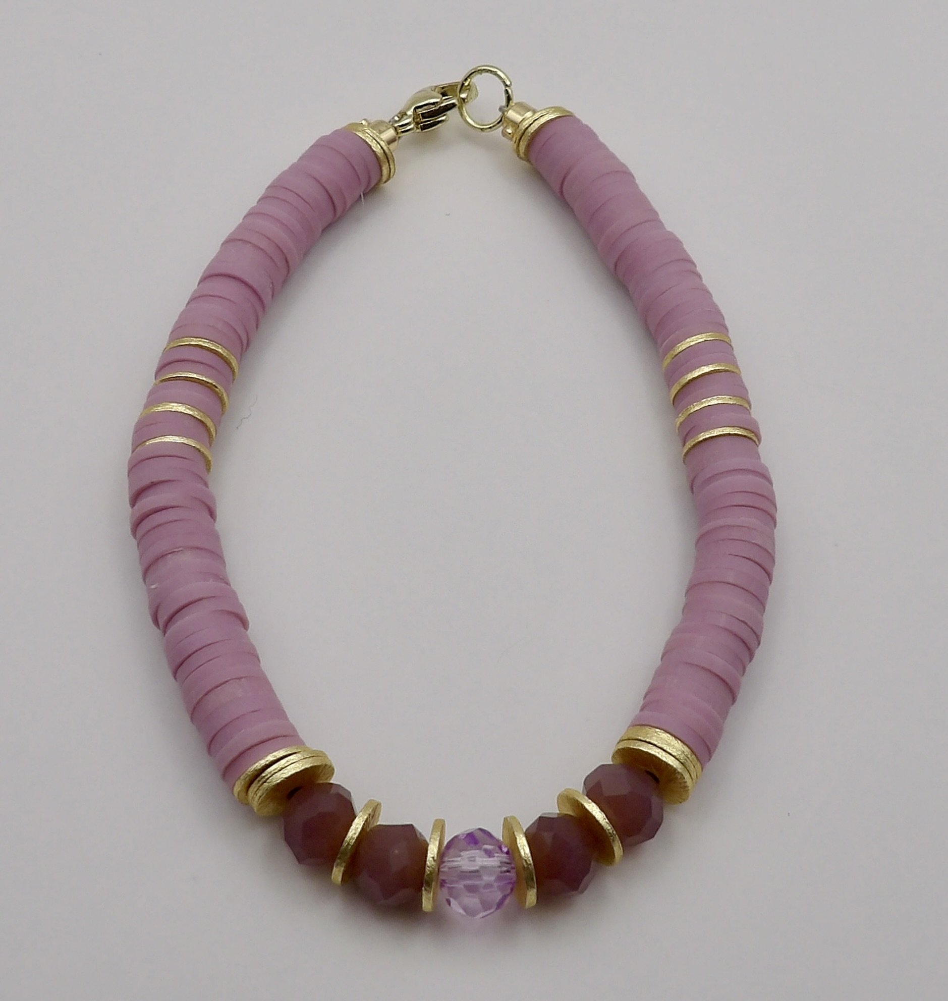 close-up of the centerpiece: a clear purple glass bead framed by mauve glass and 14k brushed gold heishi beads.