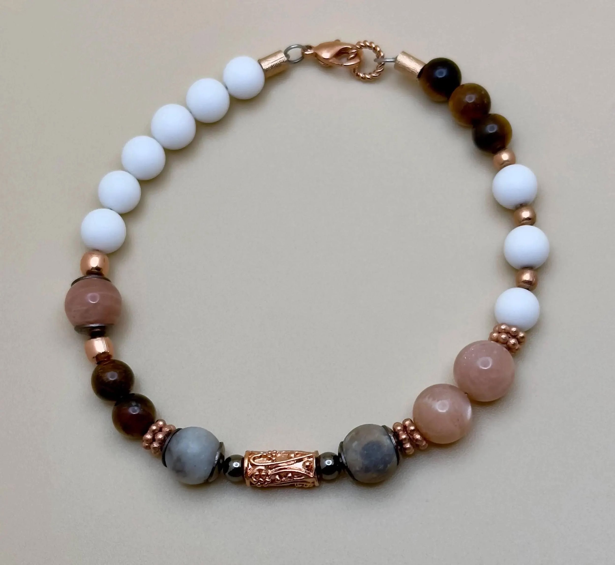 a vibrant artisan jewelry piece combining healing stones like amazonite and jade with high-shine rose gold accents.