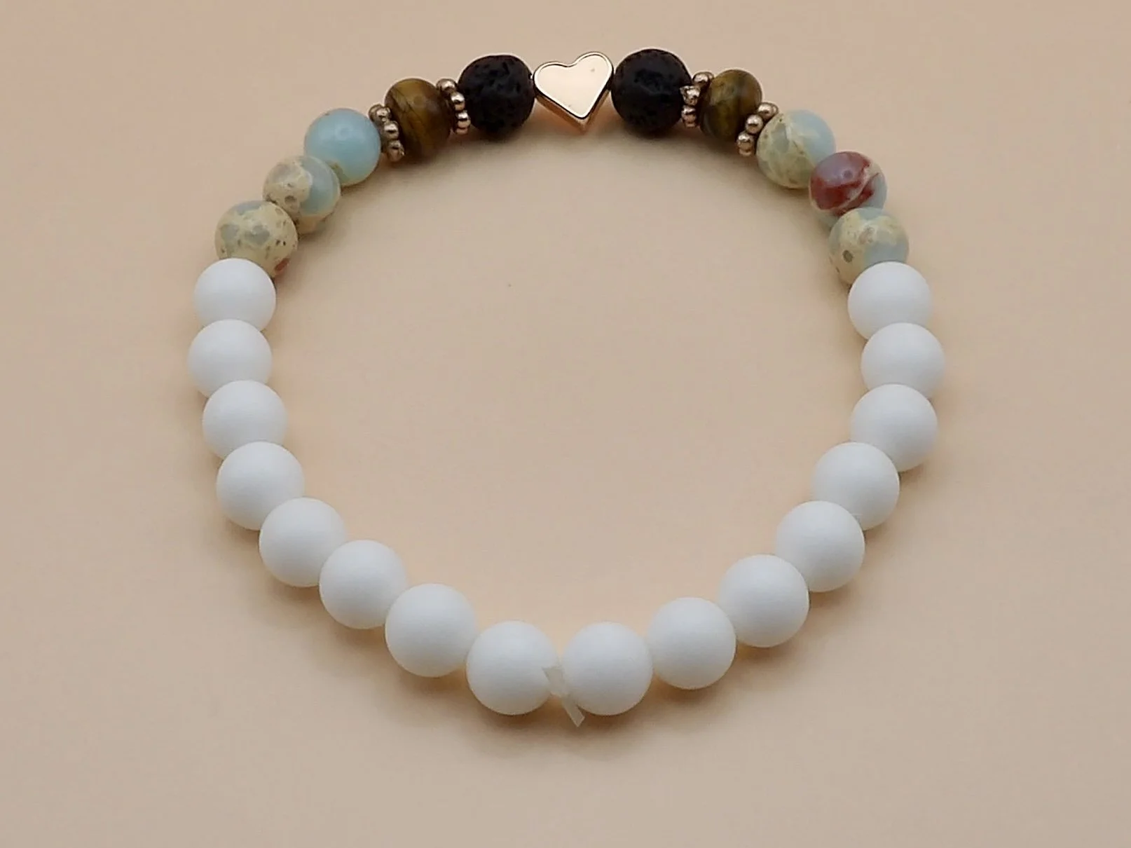 view of the smooth matte white jade beads comprising the back half of the rose gold heart mixed gemstone bracelet.