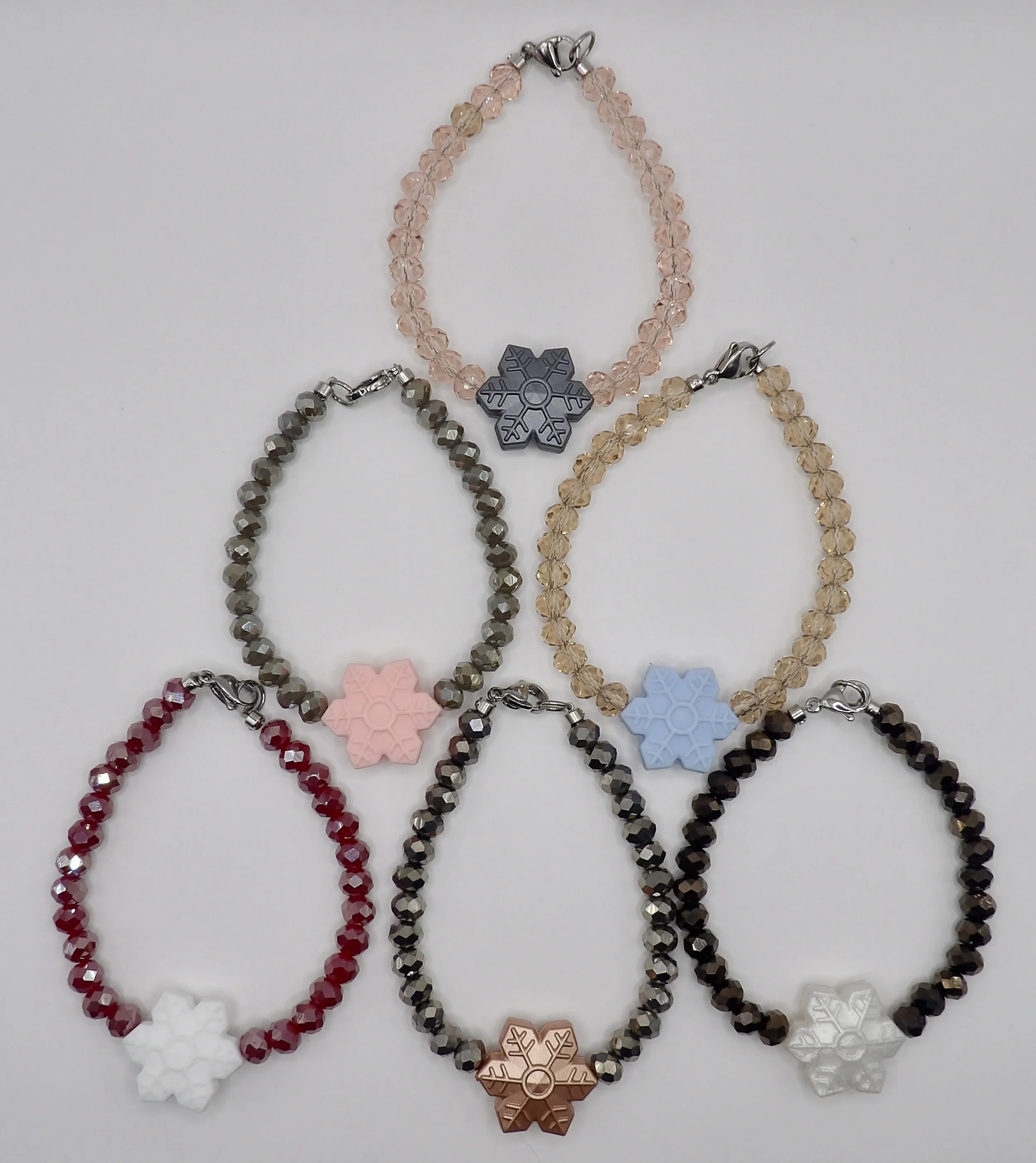 all 6 colors of the handmade snowflake bracelet with faceted glass beads and stainless steel clasps, shown together in a collection.