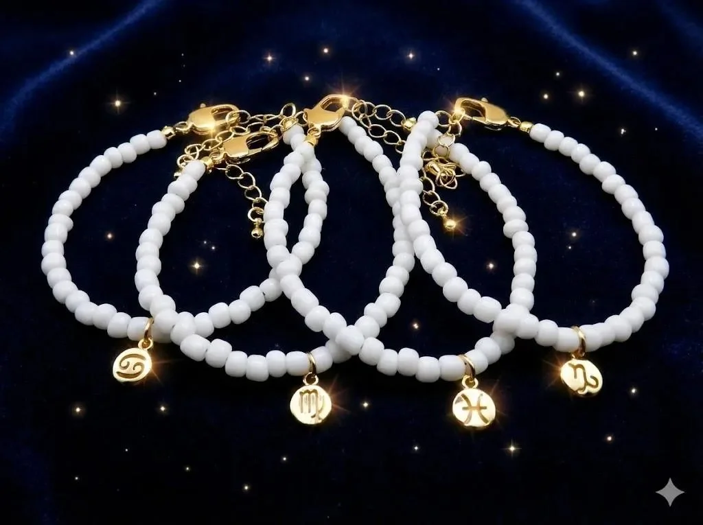 dainty white seed bead bracelet with a polished 18k gold plated astrology charm on a soft, airy background.