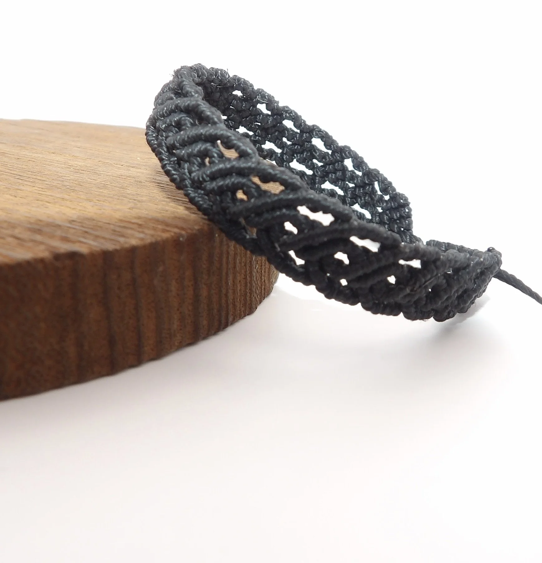 close-up detail of the intricate scrollwork weave (s-curve and half-heart pattern) on the black 0.8mm waxed polyester micro macrame bracelet.