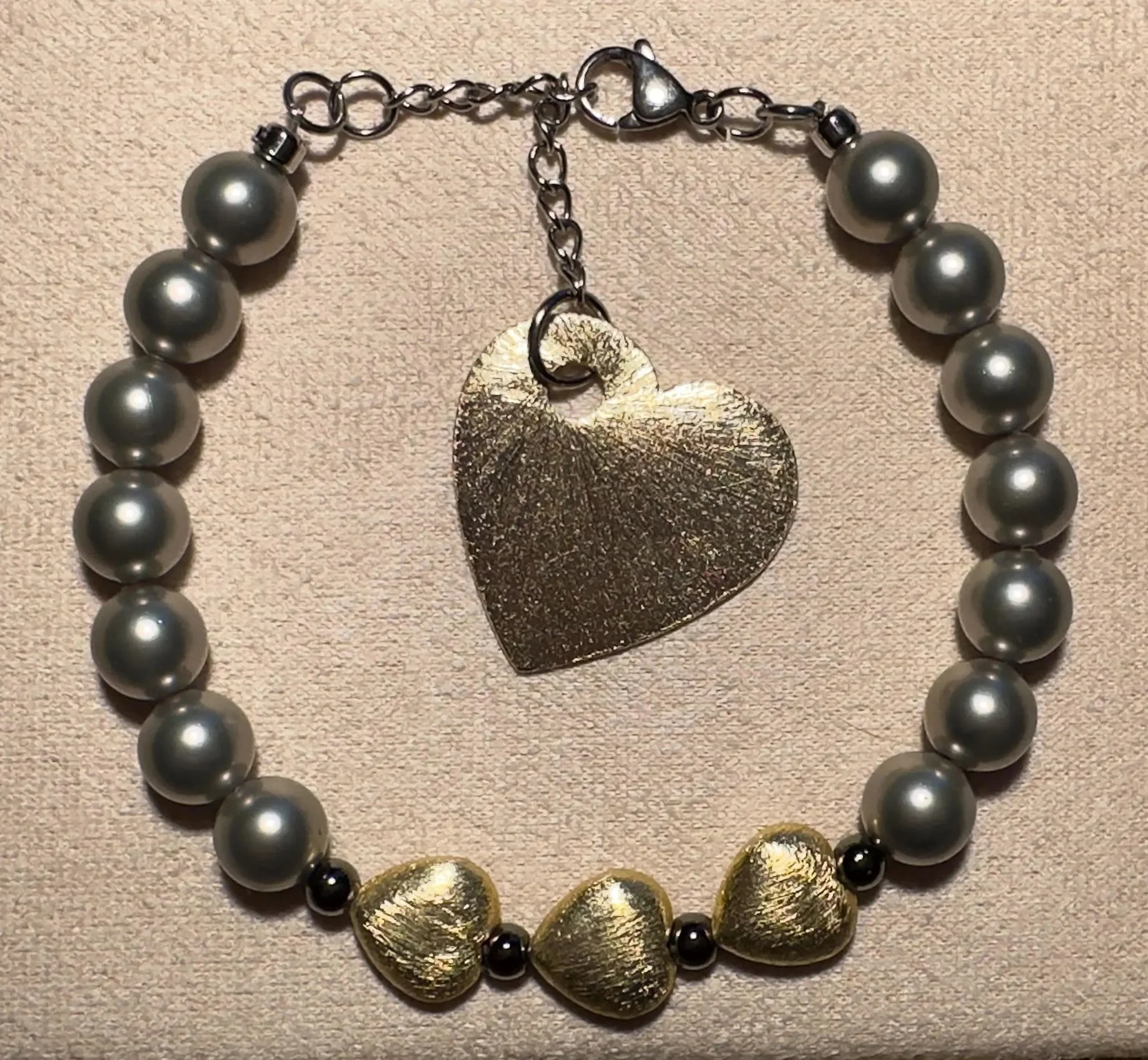 adjustable drawstring bracelet with high-shine hematite beads and delicate brushed gold heart focal points.