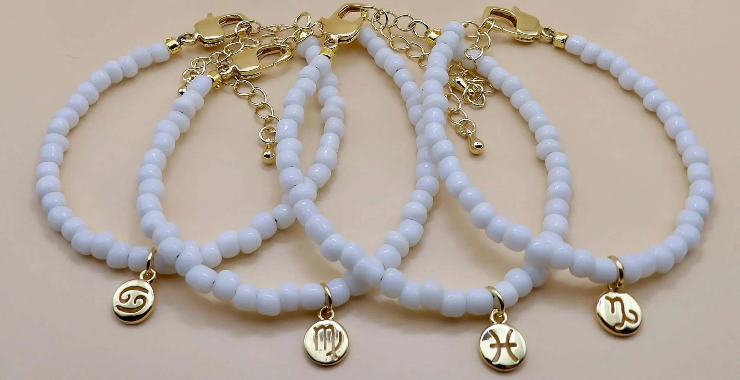 stacking zodiac jewelry with an 18k gold plated charm and tiny white glass seed beads for a refined look.