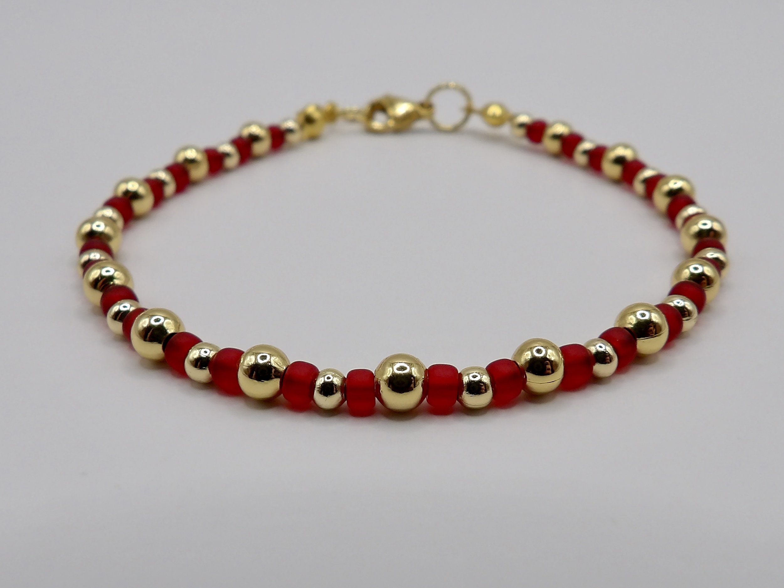 detail view of the handmade bracelet with alternating matte red 3mm seed beads and 2mm/4mm solid 18k gold beads.