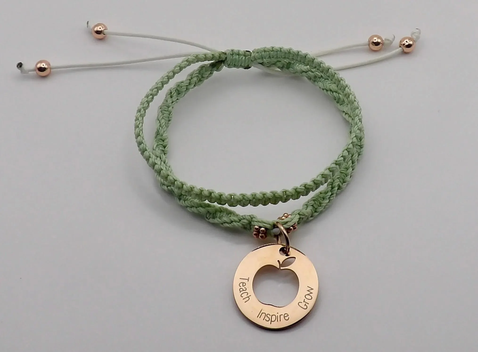handcrafted double-strand macramé bracelet in a soft botanical palette with a rose gold inspirational teacher charm.