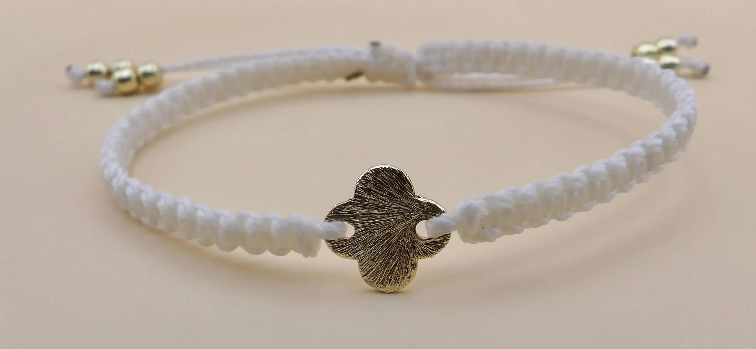 detailed view of the square-proportioned Greek cross focal bead nestled securely in a professional, artisan-made macramé band.