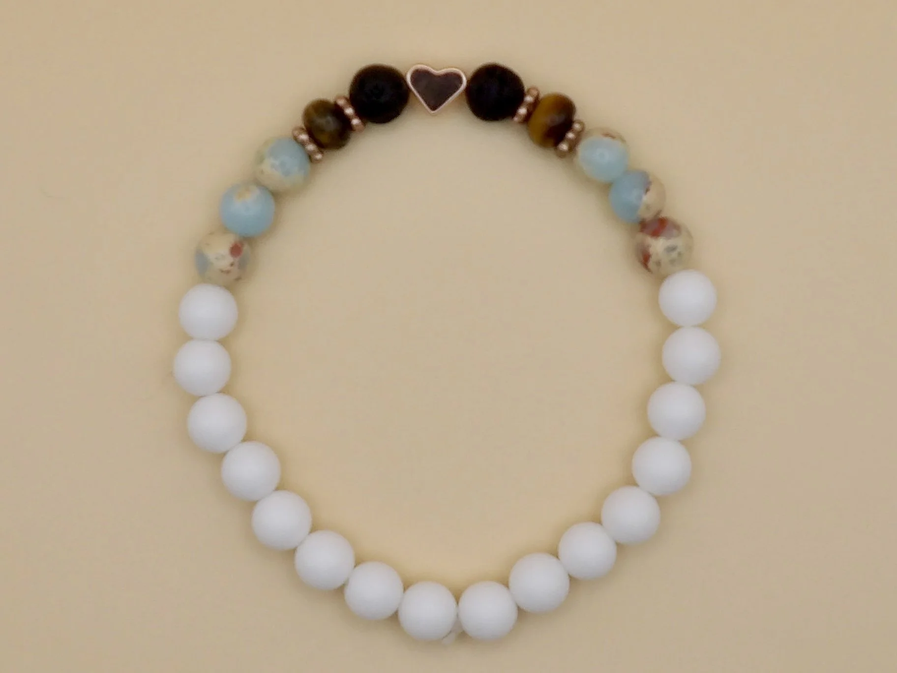 view of the smooth matte white jade beads comprising the back half of the rose gold heart mixed gemstone bracelet.