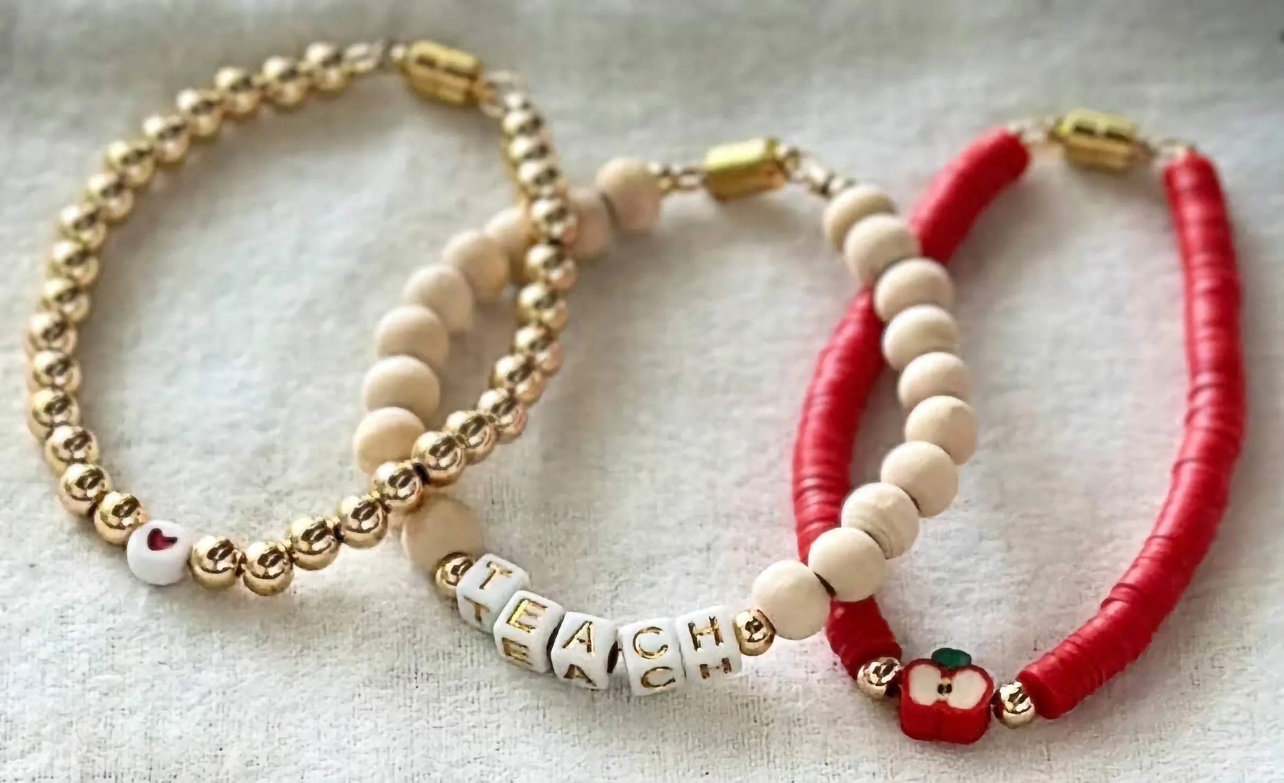 product image of a handmade bracelet for teachers, with a heart, apple, and teach spelled out in beads