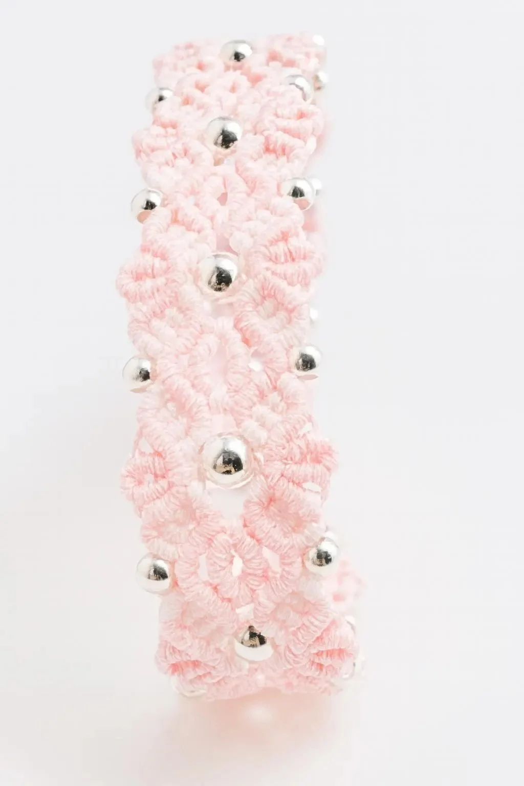 a highly detailed botanical jewelry piece showing the technical micro-weave of a pink flower motif and silver accents.