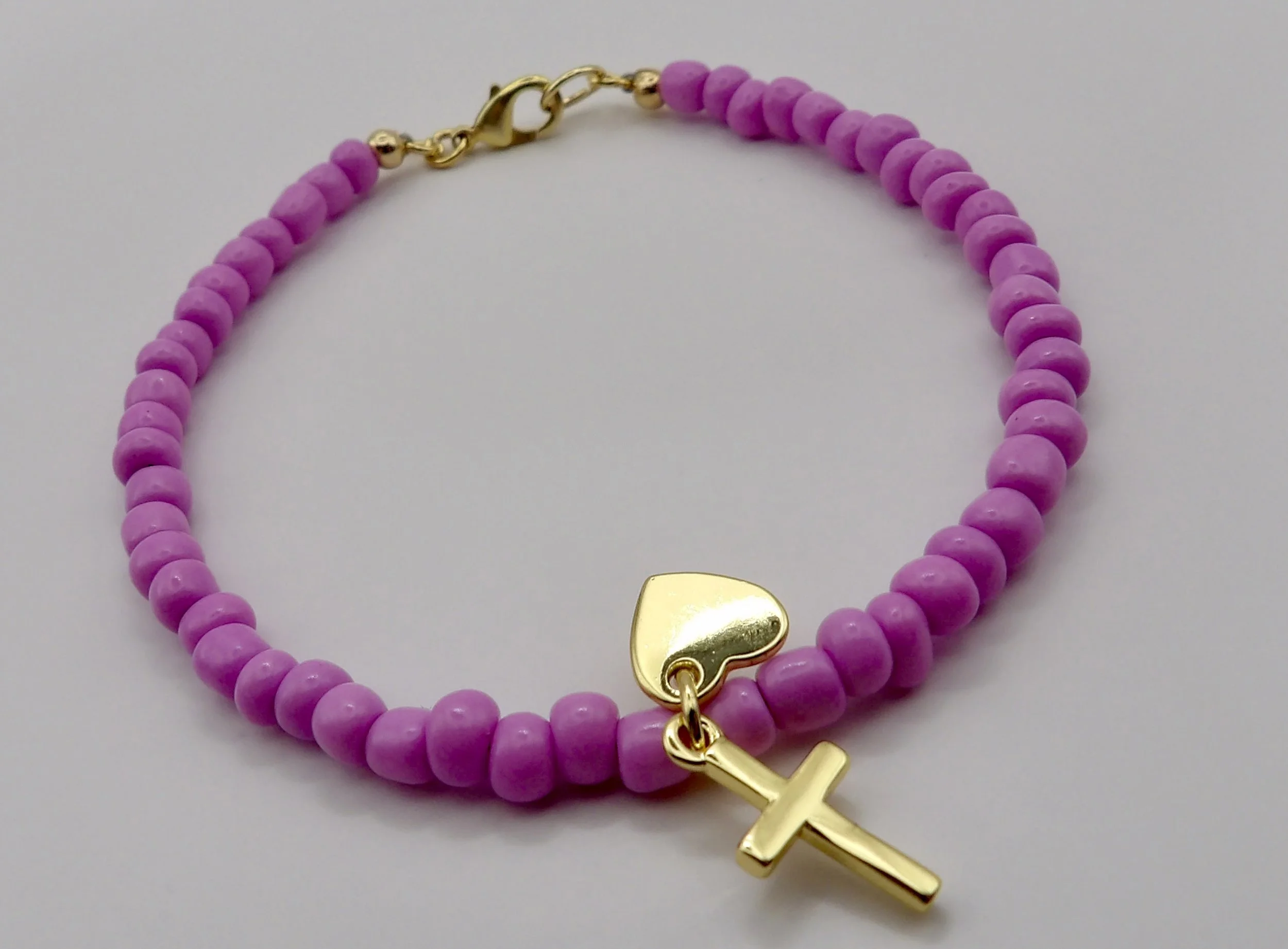 woman wearing the dainty lilac and gold charm bracelet, a meaningful symbol of faith and love.