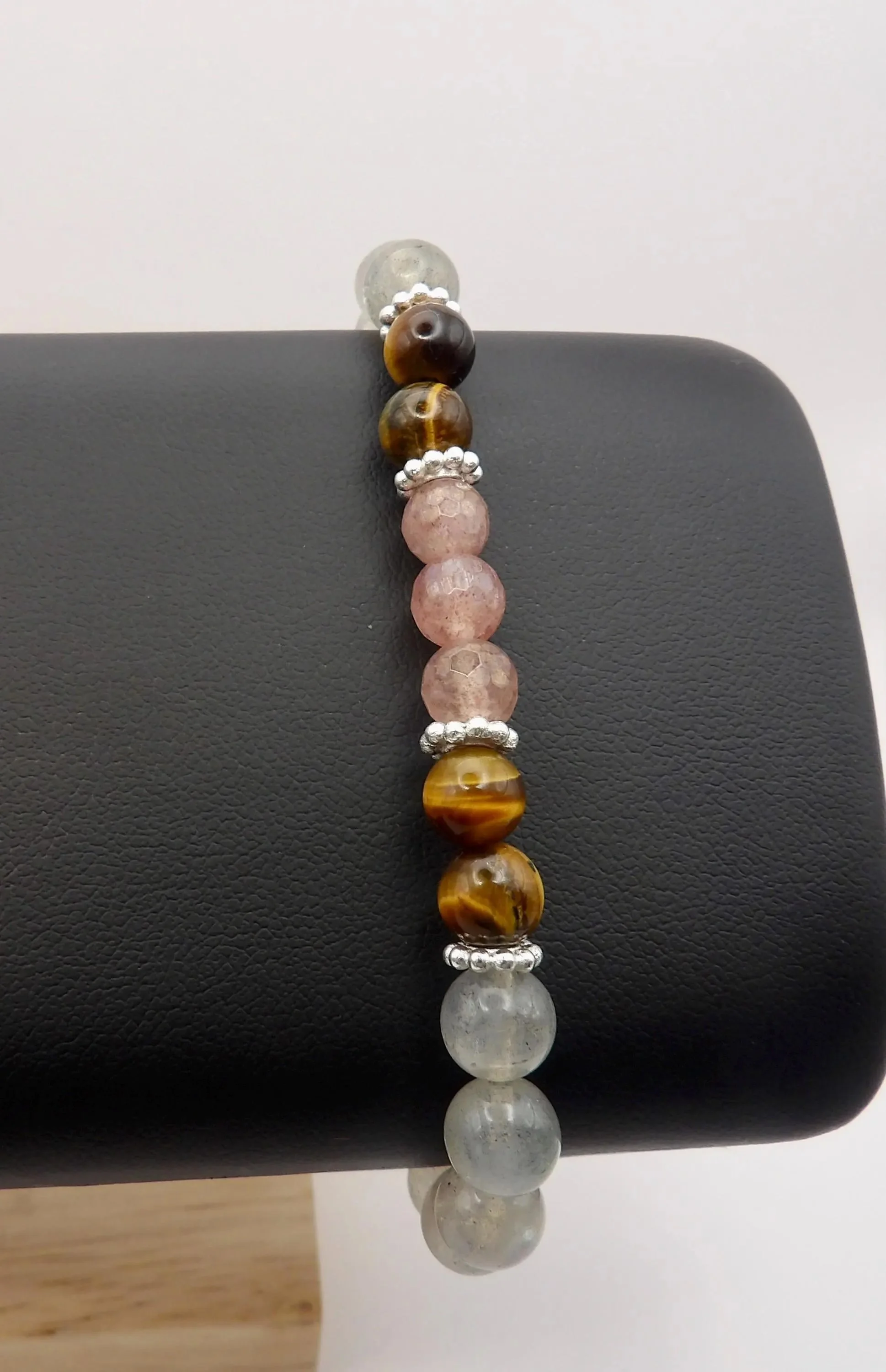 close-up of the survivor’s bloom bracelet highlighting the unique internal fractures of the strawberry quartz next to the reflective sheen of the silver daisy.