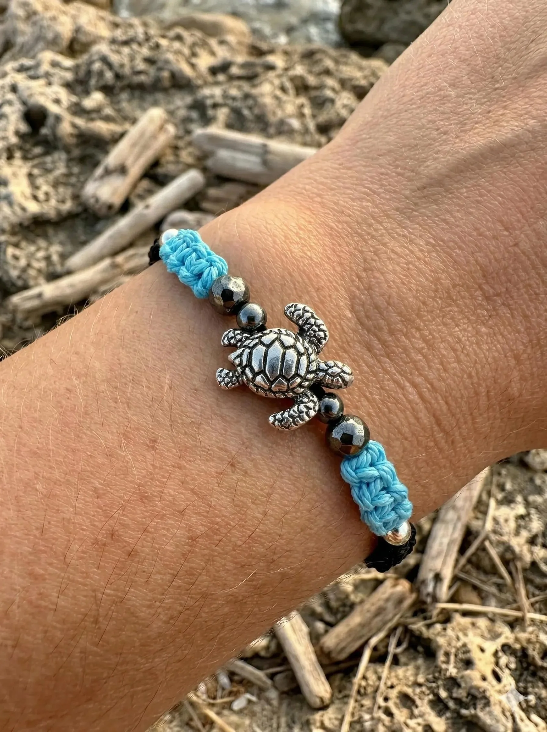 the ocean soul bracelet featuring a genuine .925 sterling silver sea turtle charm on a waterproof blue and black macramé cord.