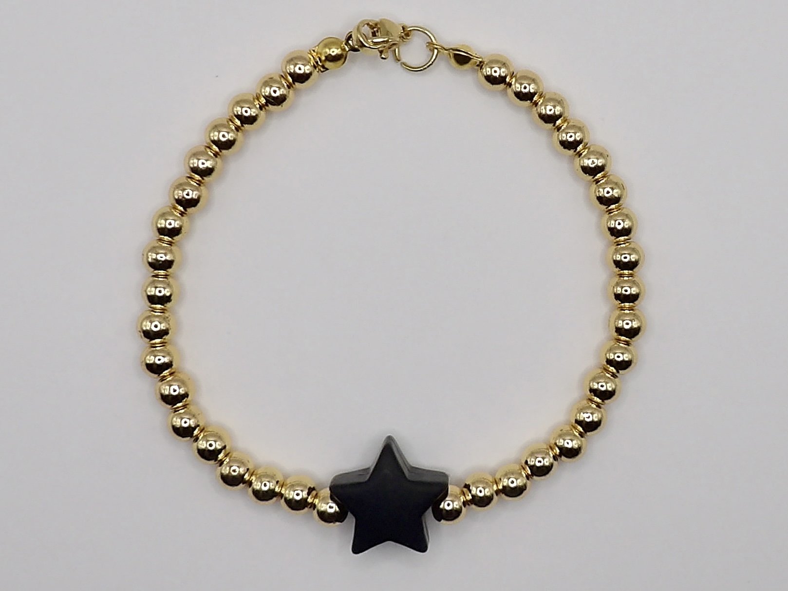 Handmade 18k solid gold beaded bracelet featuring a matte black silicone star charm. Playful luxury jewelry gift.