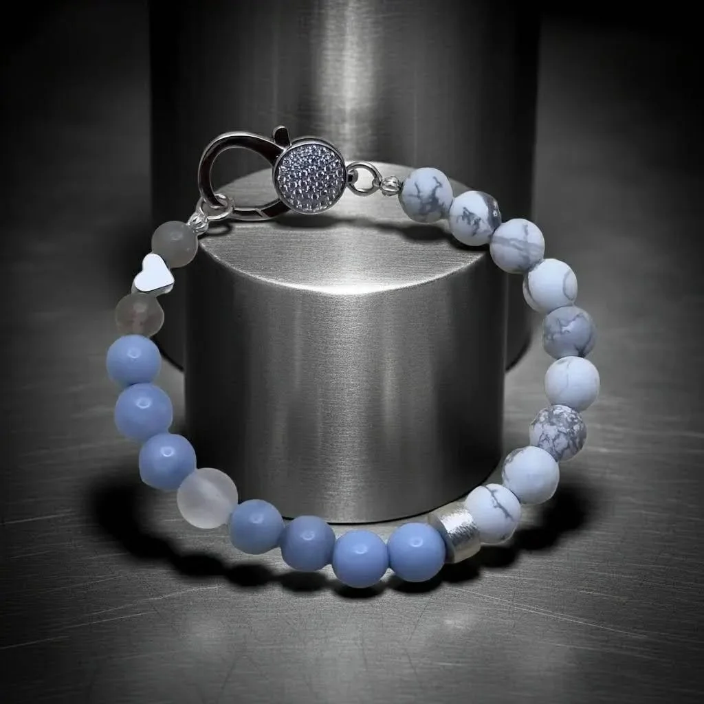 a luxury gemstone jewelry piece highlighting the sparkling pavé focal point against a backdrop of matte white and airy blue stones.