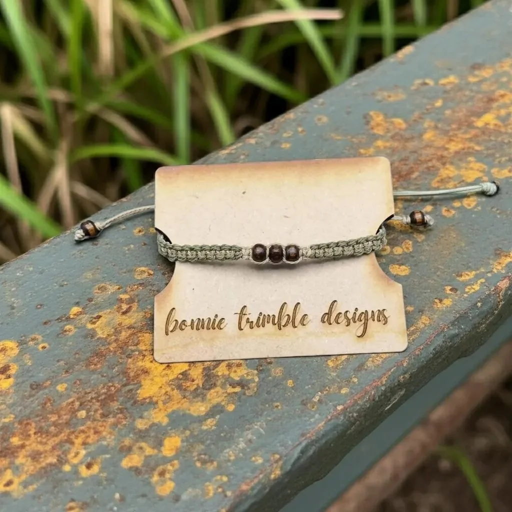 a rugged, adjustable utility bracelet showing the tactile texture of the hand-woven cord and organic wood elements.