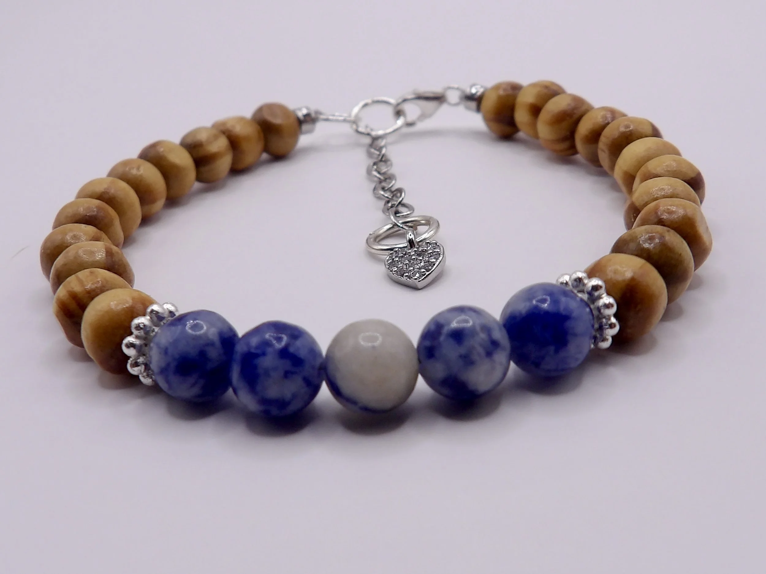 close-up detail showing the five blue sodalite beads nestled between two .925 sterling silver daisy spacer beads on the wood bracelet.
