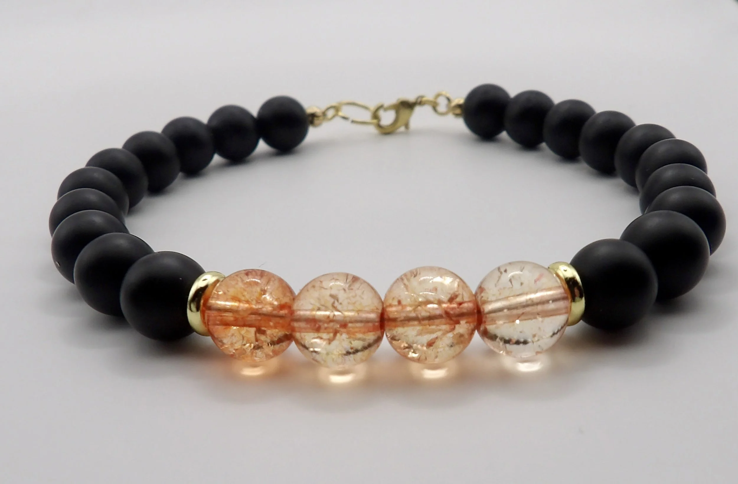 handmade 18k solid gold bracelet featuring 8mm matte black onyx beads and a pink crackle quartz centerpiece.