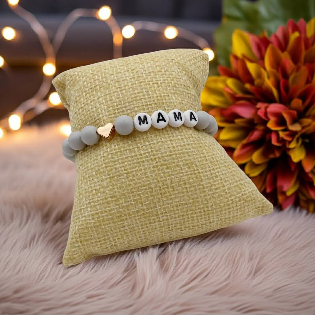 gray matte beaded bracelet spelling “mama” with letters, featuring a central shiny rose gold heart accent bead.