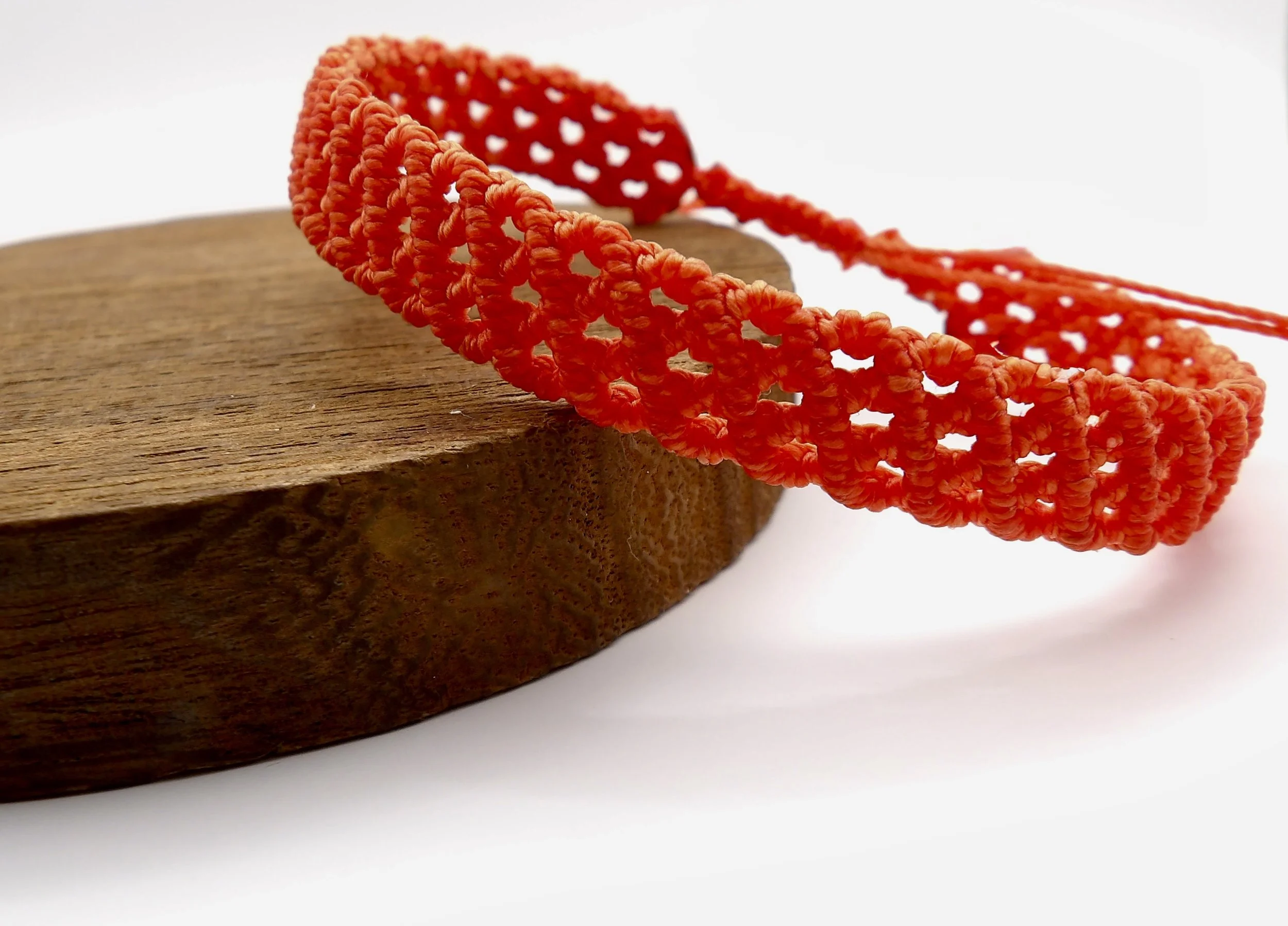A macro close-up of the intricate micromacrame knotwork, showing the fine details of the woven dark orange strands.