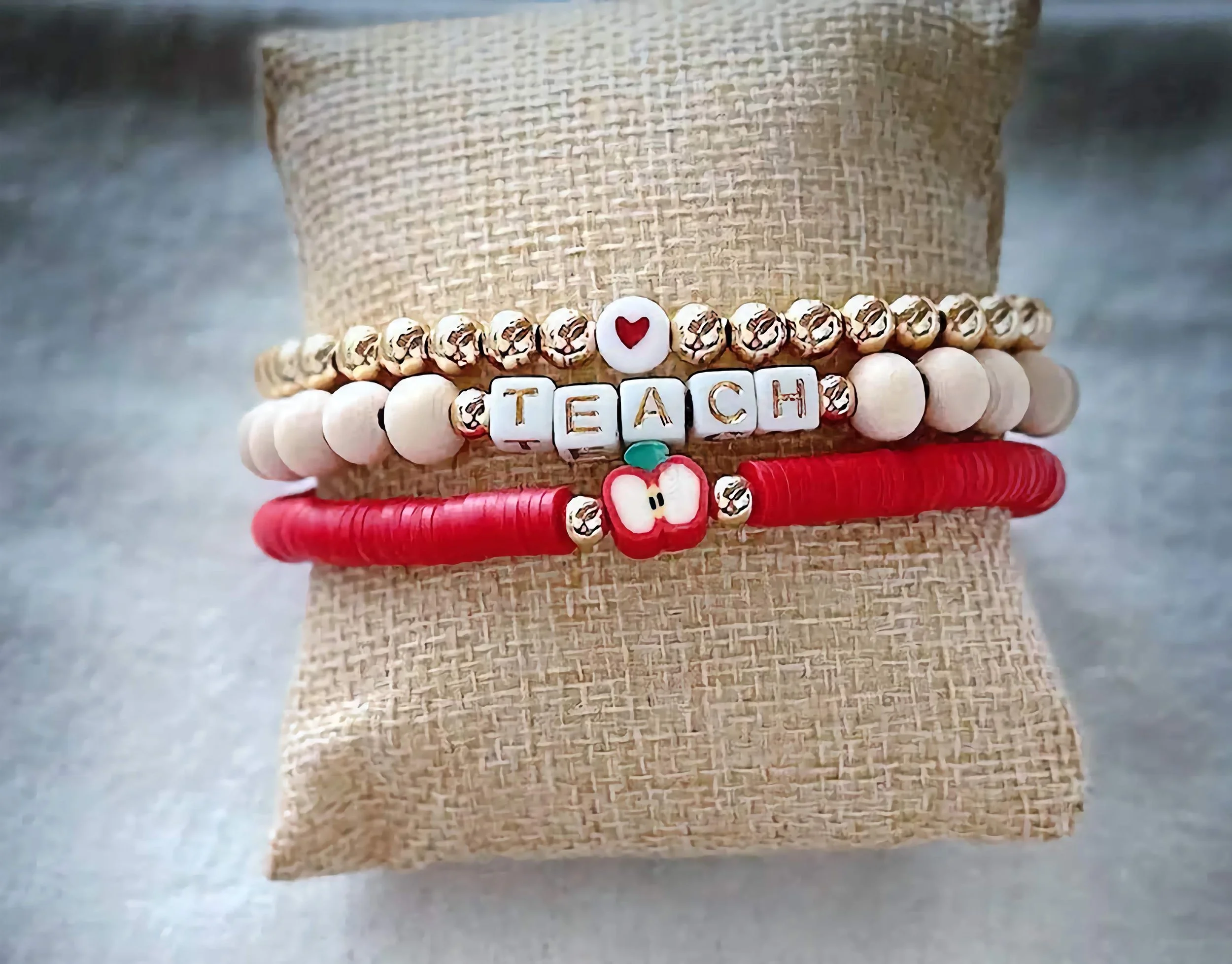 product image of a handmade bracelet for teachers, with a heart, apple, and teach spelled out in beads