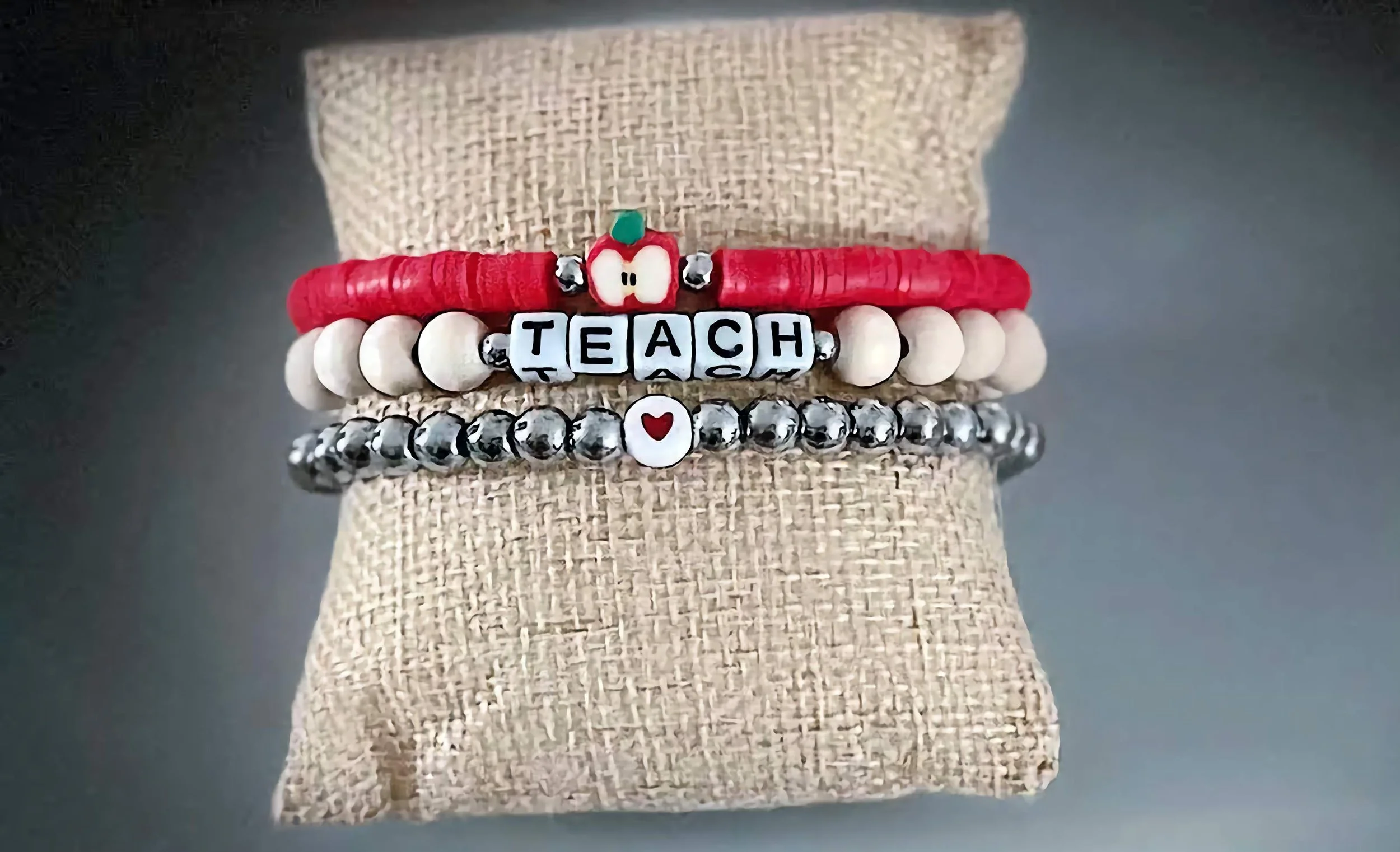 product image of a handmade bracelet for teachers, with a heart, apple, and teach spelled out in beads