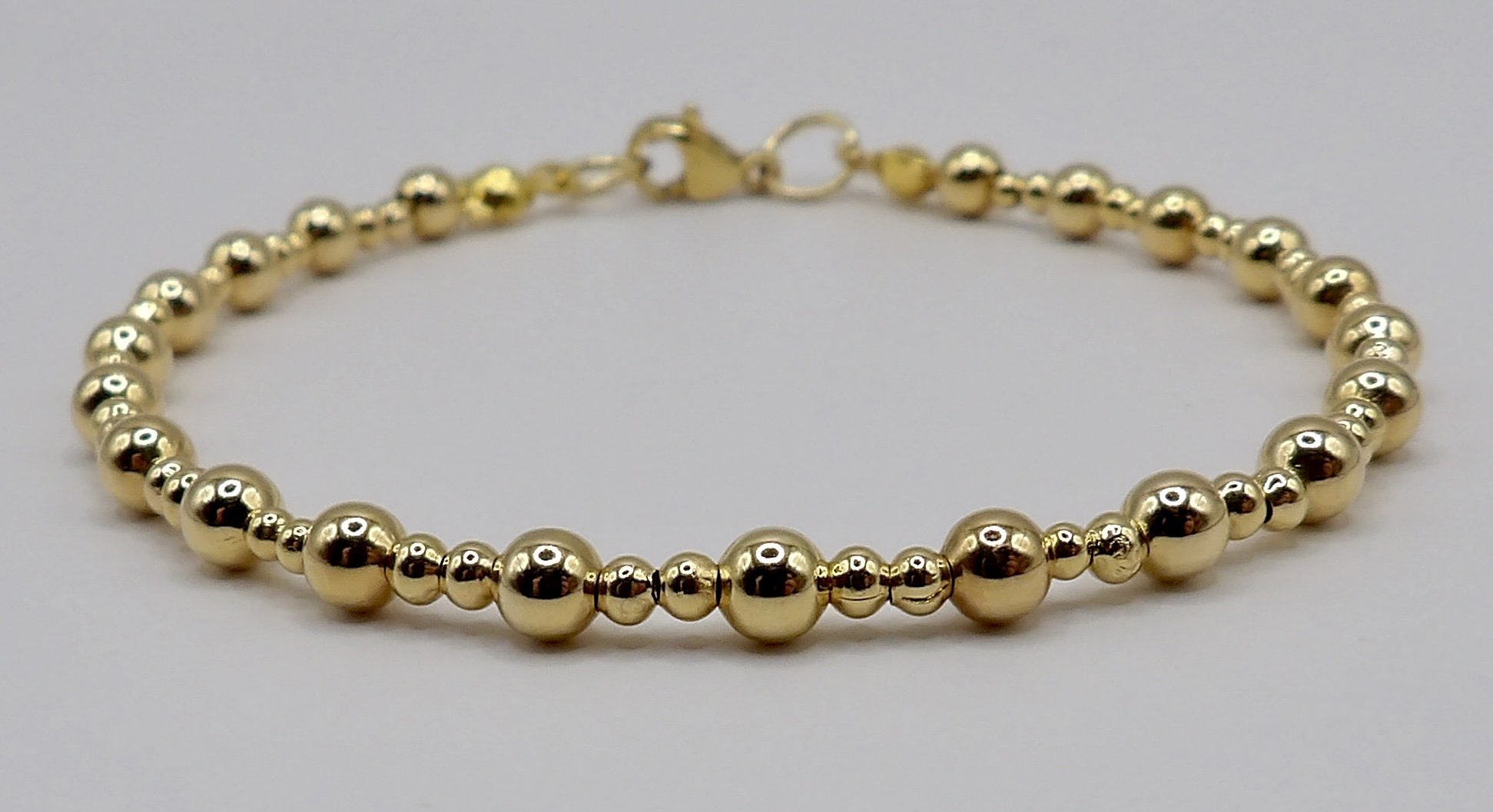 detail view of the all solid 18k gold bracelet showing the alternating pattern of 4mm and 2mm smooth round beads.