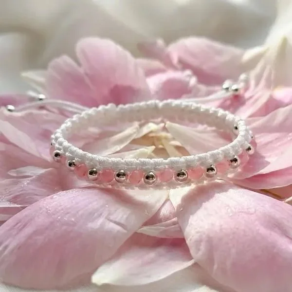 white macramé bracelet featuring sterling silver details and pink beads.