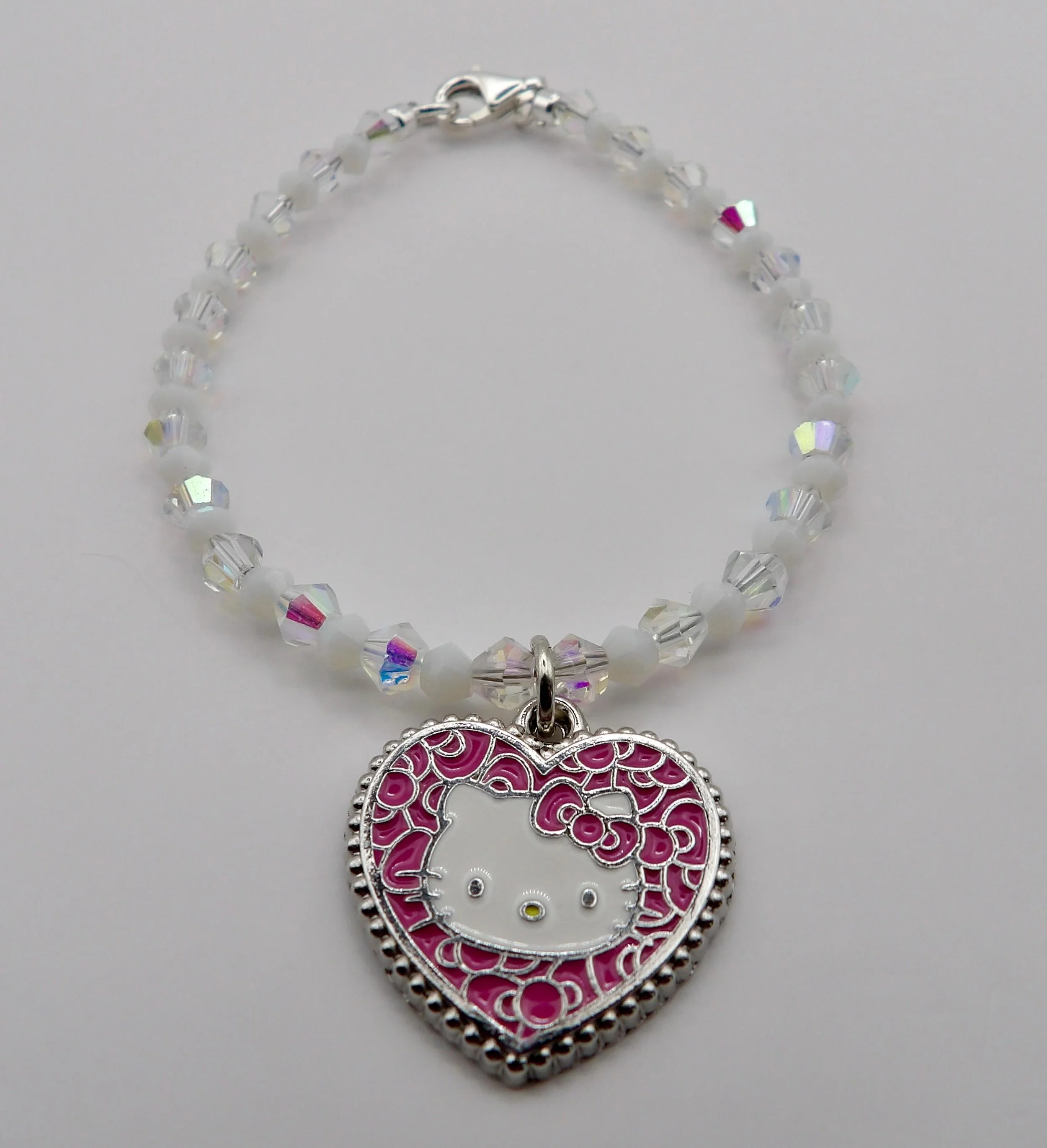 handcrafted hello kitty inspired jewelry with a mosaic pink heart focal and premium sterling silver beads on a soft pink background.