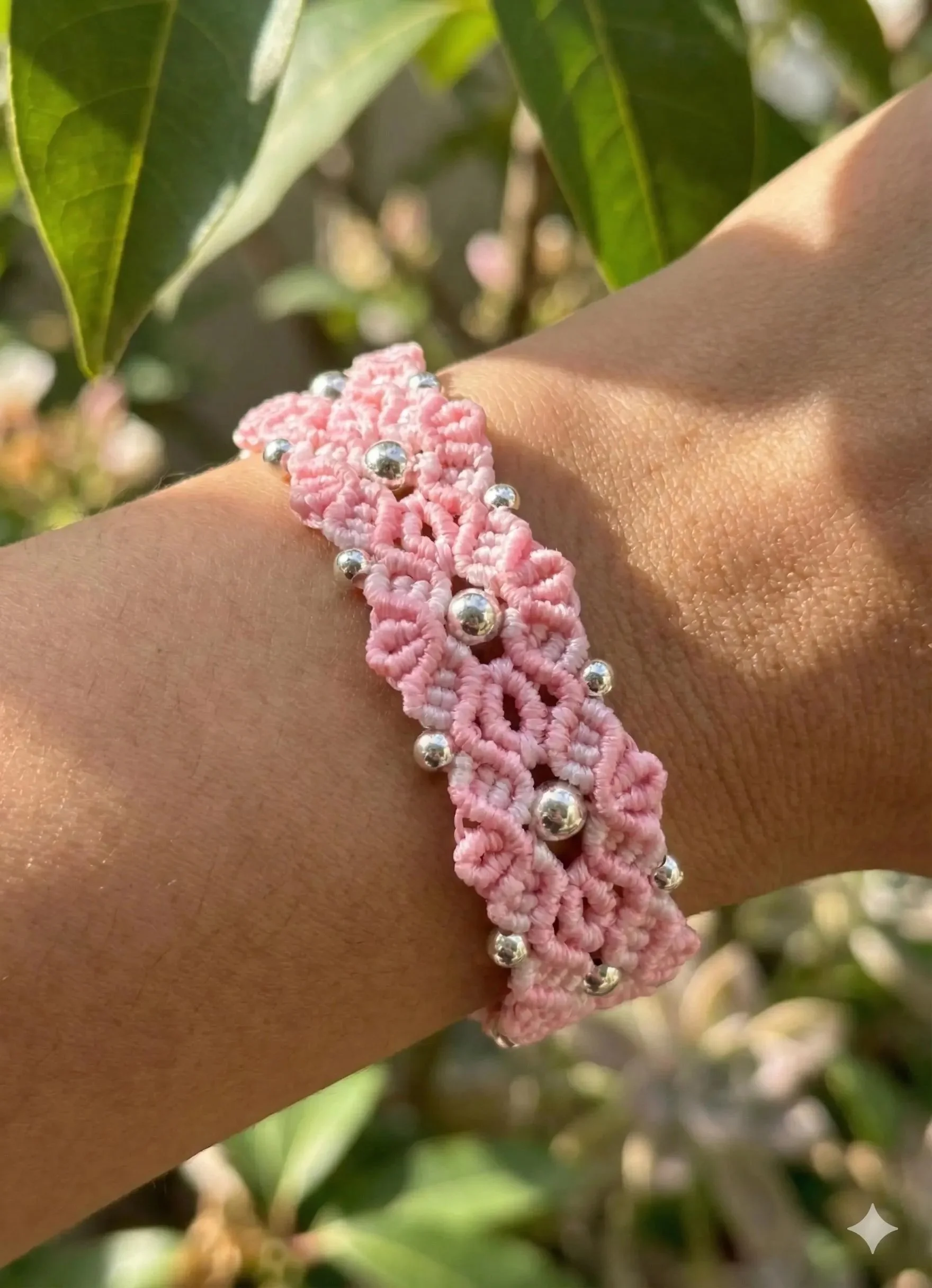 the woven bloom bracelet featuring an intricate hand-knotted micro-macramé flower in soft light pink with sterling silver centers.